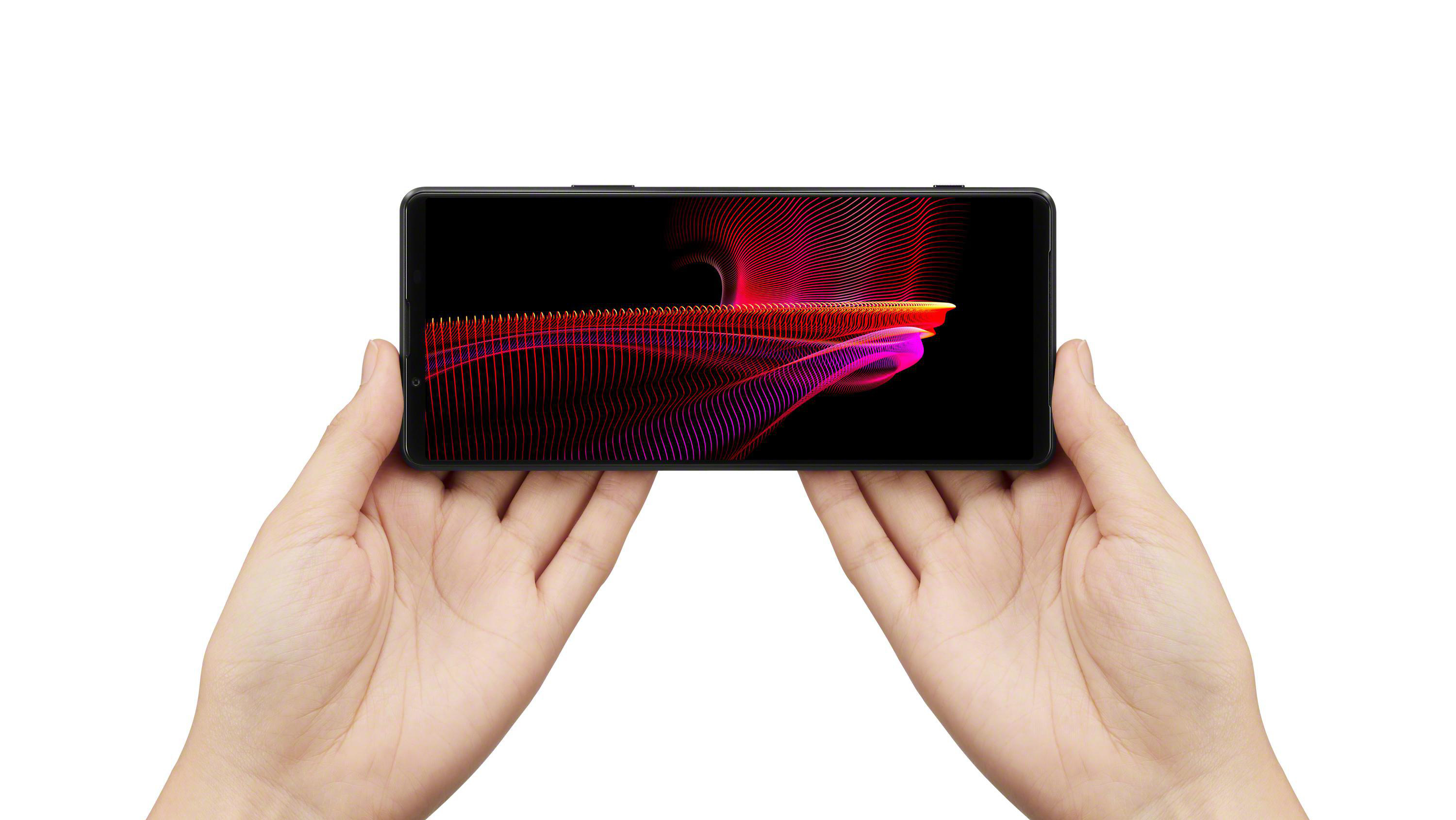Hände halten ein Telefon, das ein farbenfrohes abstraktes Bild auf einem schwarzen Bildschirm zeigt.