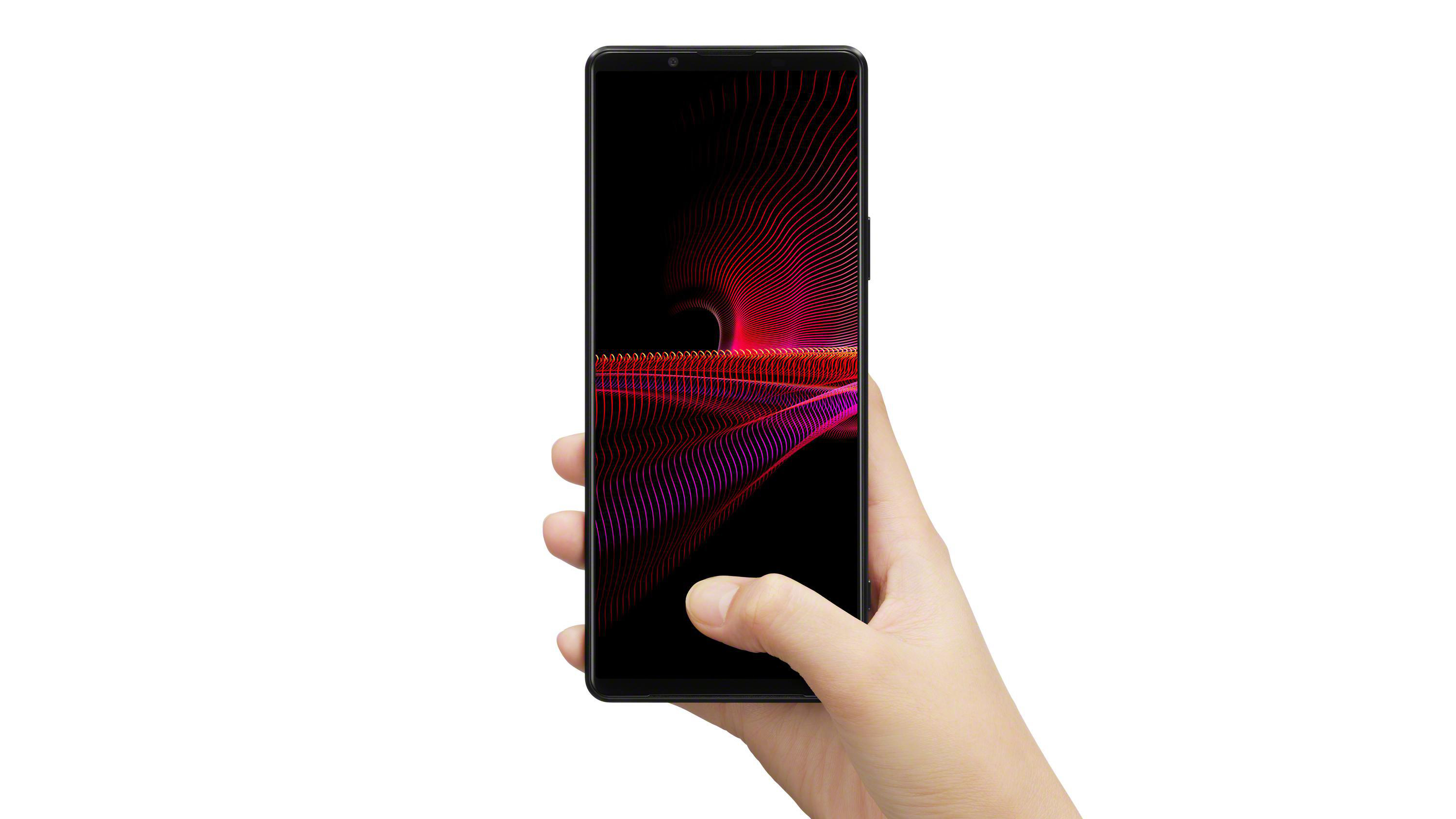 Eine Hand hält ein schwarzes Smartphone. Der Bildschirm zeigt eine rot-violette Grafik.