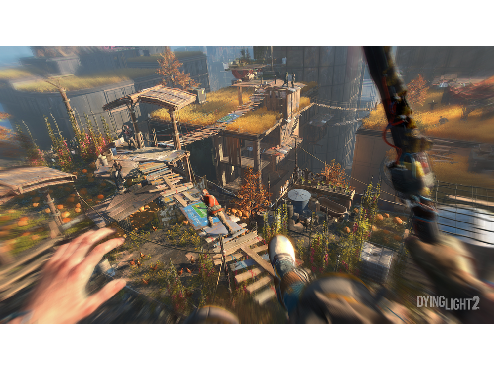 Vista en primera persona de una escena de videojuego con edificios y una persona en tirolesa.