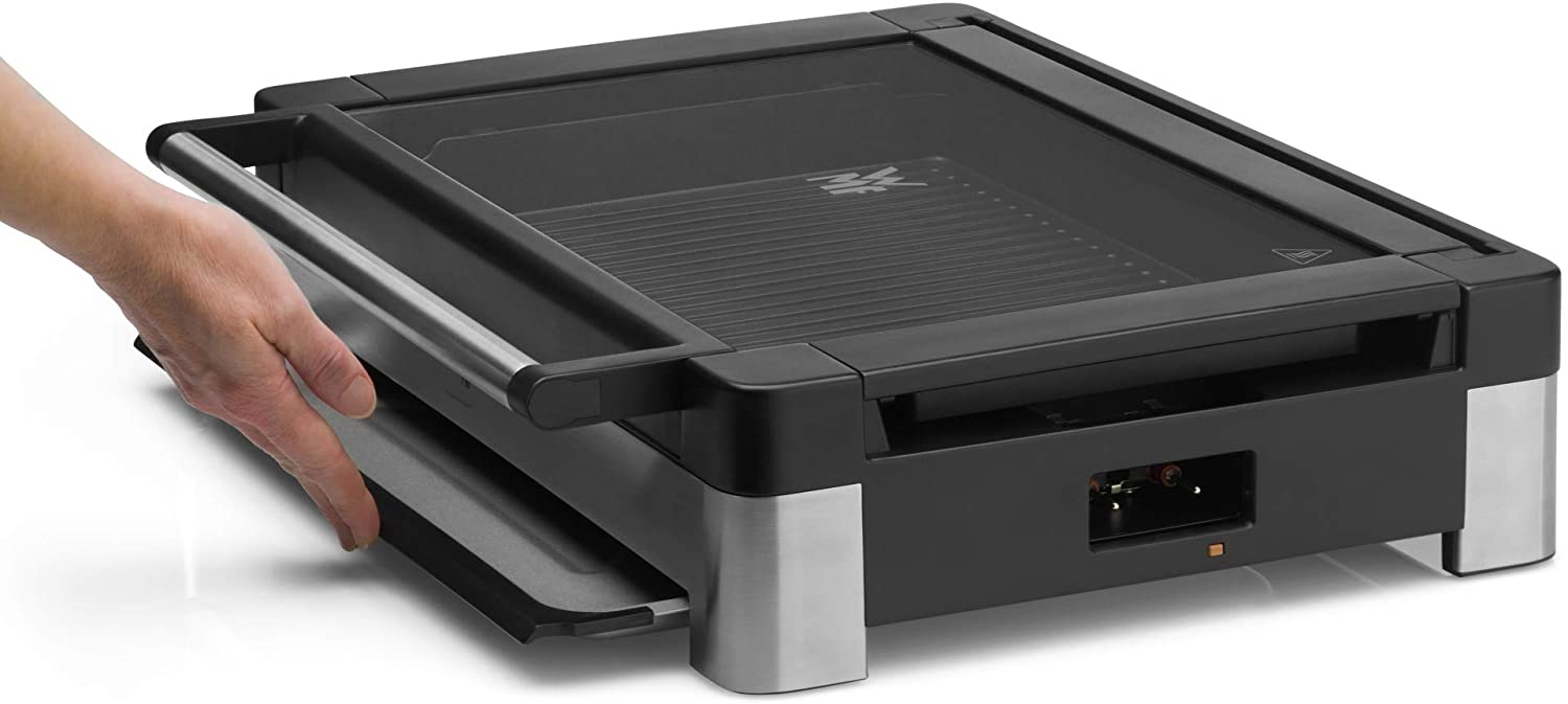 Eine Hand zieht eine Schublade an einem schwarzen und silbernen Elektrogrill heraus. Der Grill steht auf weißem Grund.