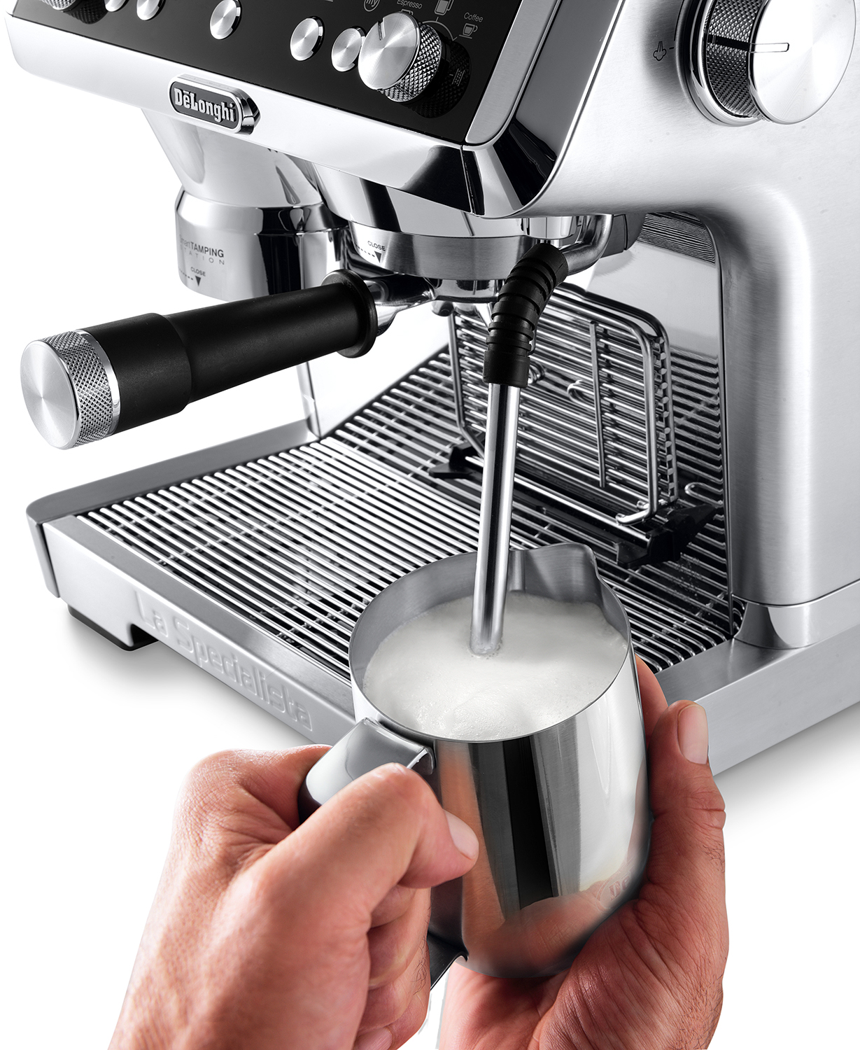 Een zilveren espressomachine die melk stoomt in een metalen kan, vastgehouden door een hand.