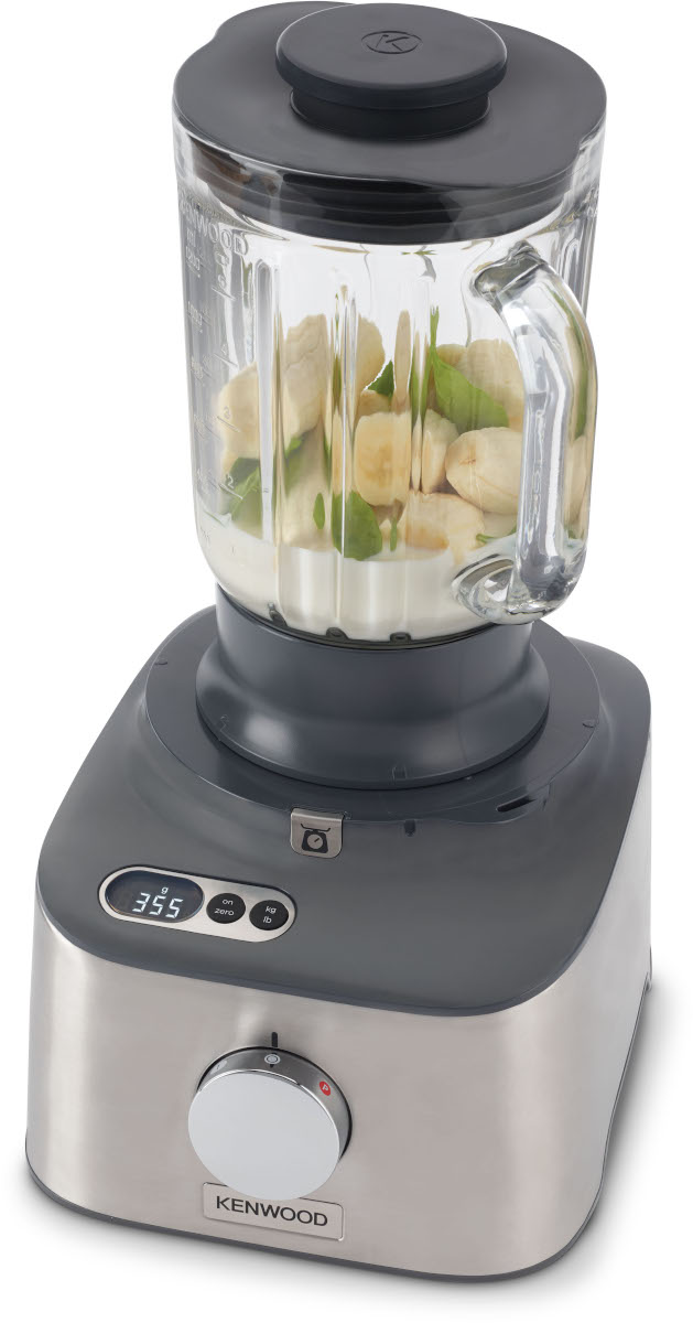 A blender with a glass jar containing bananas, spinach, and liquid sits on a gray base.