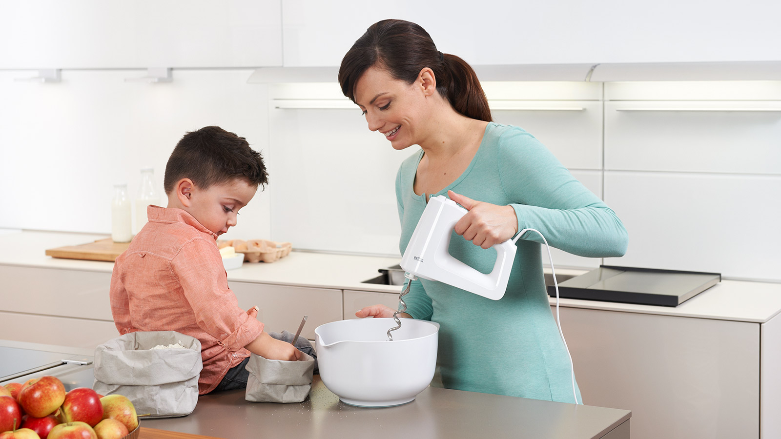 Een vrouw en een jongen bakken samen in de keuken.
