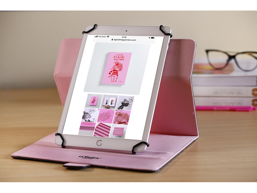 Tableta en una funda rosa sobre un escritorio. La pantalla muestra una portada de libro.