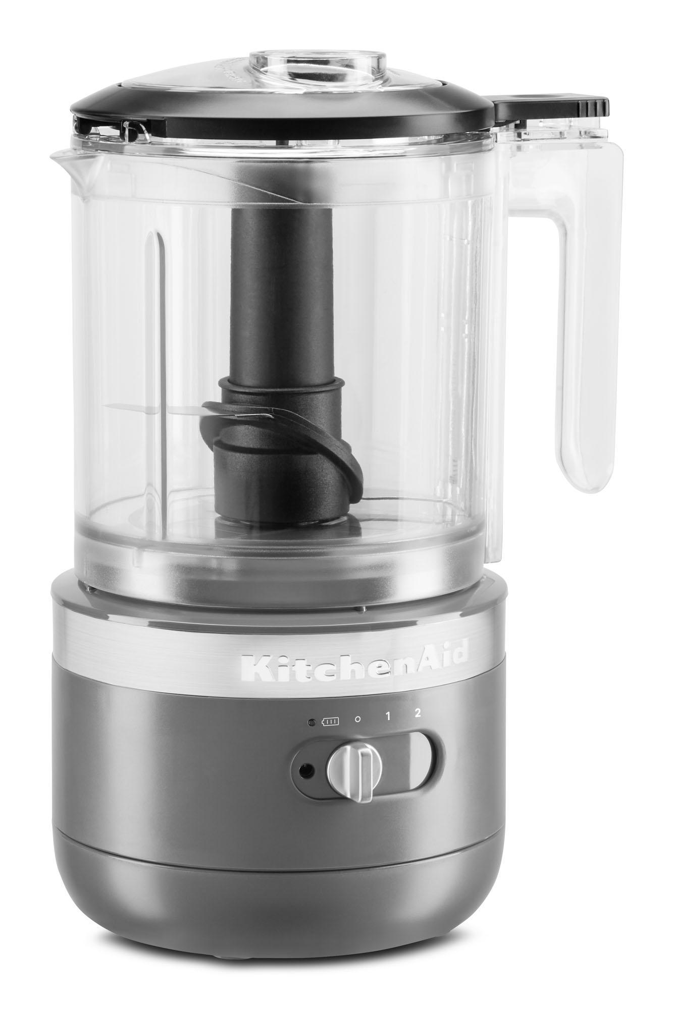 Eine KitchenAid Küchenmaschine mit transparentem Behälter, Griff und grauem Sockel.
