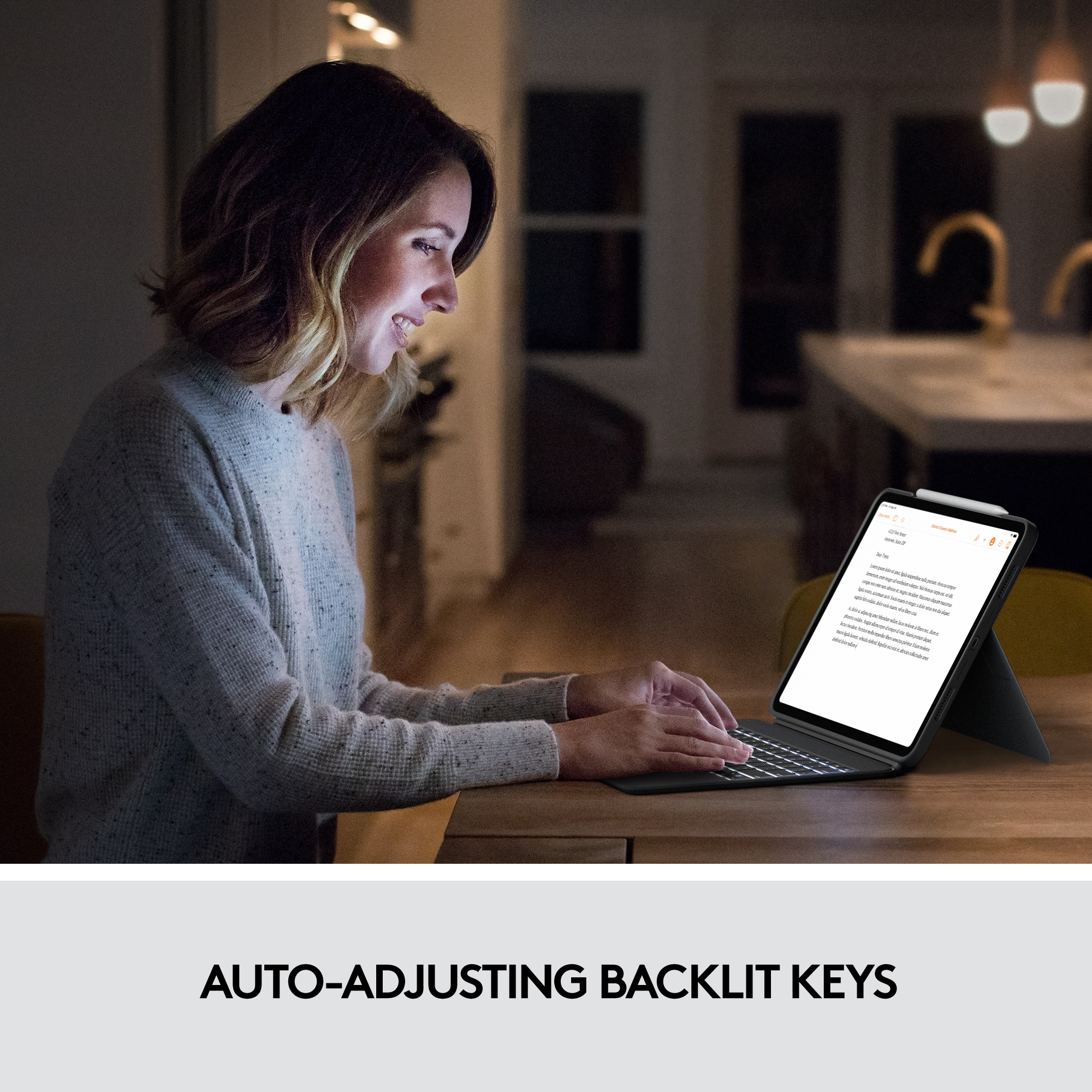 Femme utilisant une tablette avec un clavier dans une pièce faiblement éclairée, texte sur la tablette : TOUCHES RÉTROÉCLAIRÉES À RÉGLAGE AUTOMATIQUE.