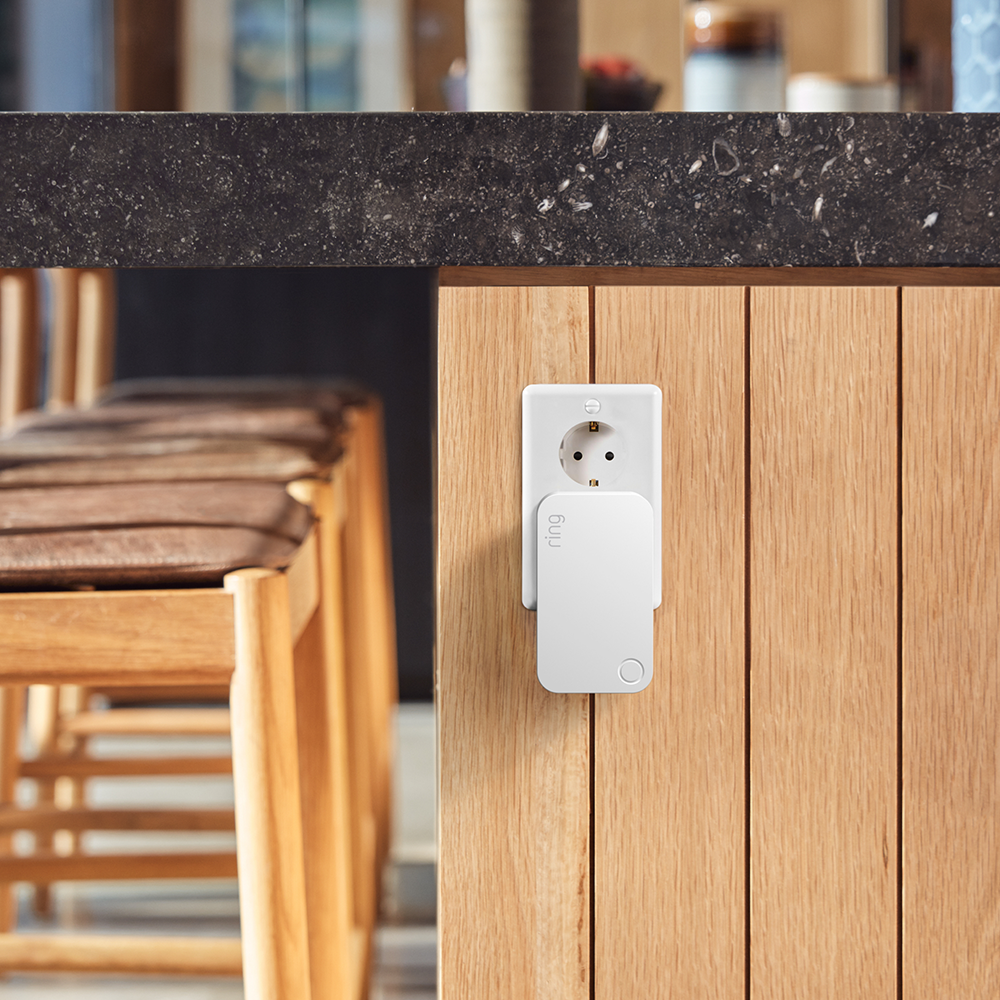 White outlet and a small white device plugged into a wooden surface.