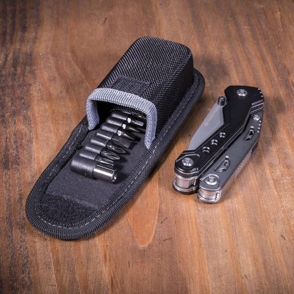Egy fekete multitool és a hordtáskája bitkészlettel egy fa felületen.