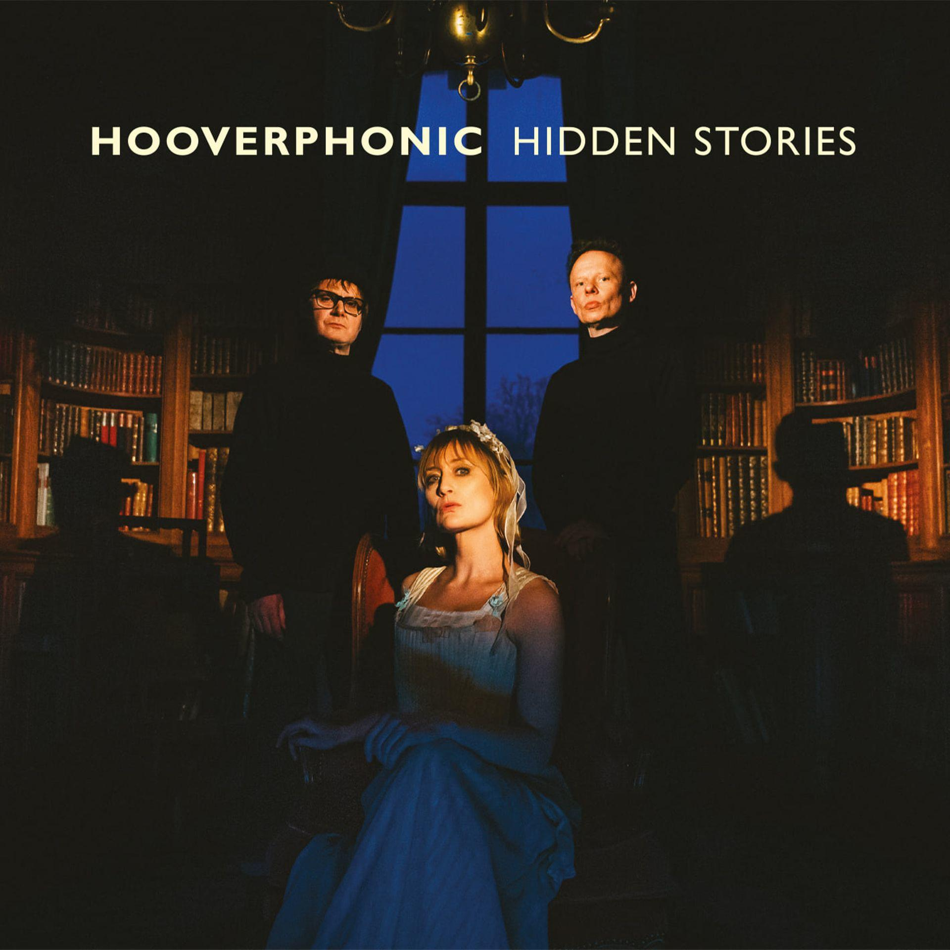 Pochette d'album : Trois personnes se tiennent dans une pièce avec des bibliothèques. Titre : Hooverphonic Hidden Stories.