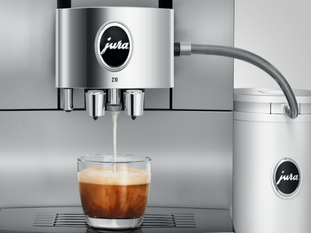 Una cafetera dispensando café en una taza de vidrio.
