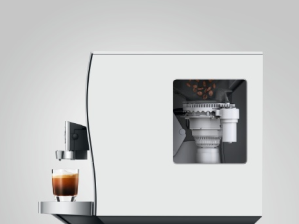Máquina de espresso con un vaso de espresso y granos de café.