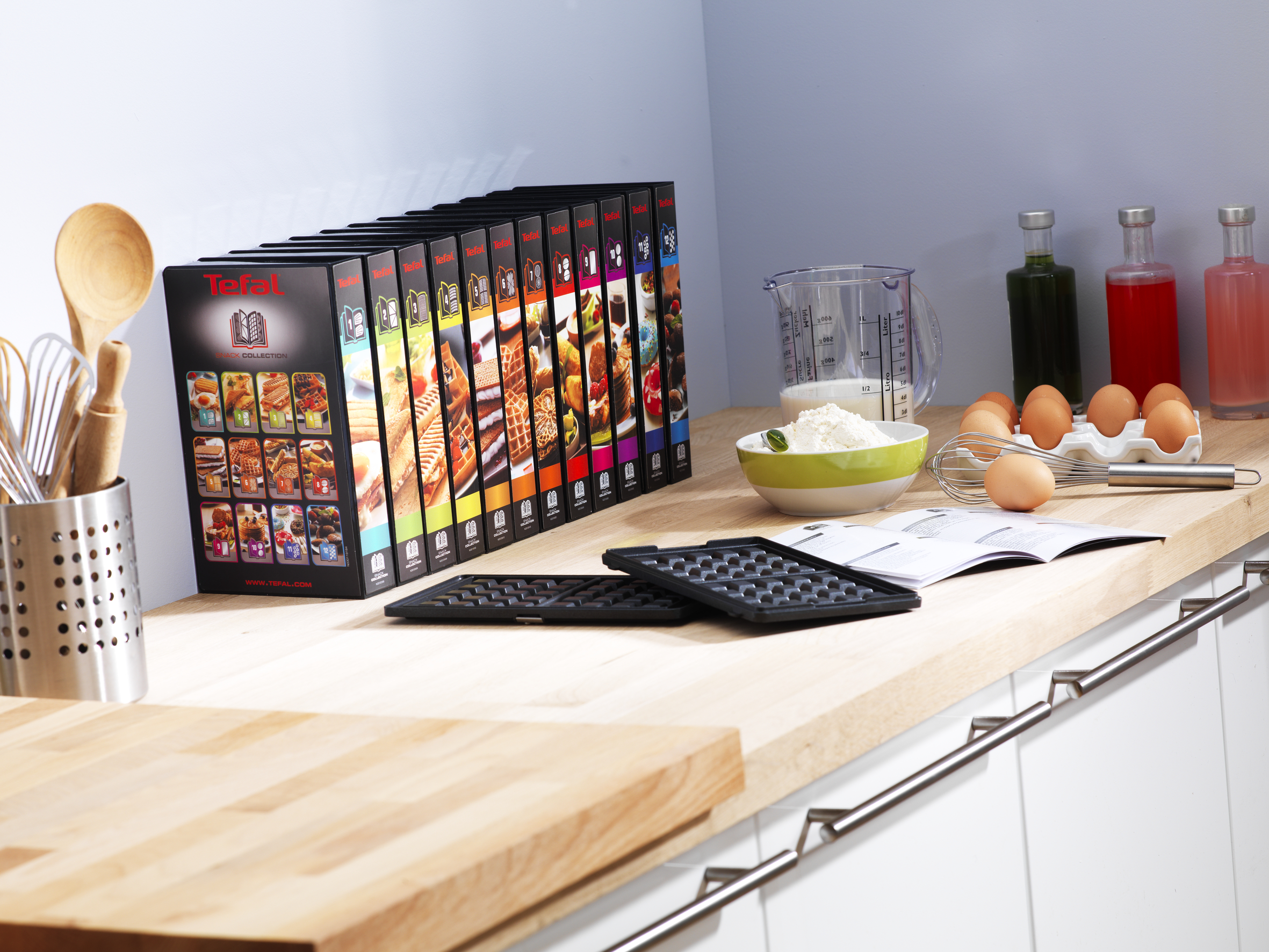 Küchentheke mit Kochbüchern, Zutaten und Waffeleisen.