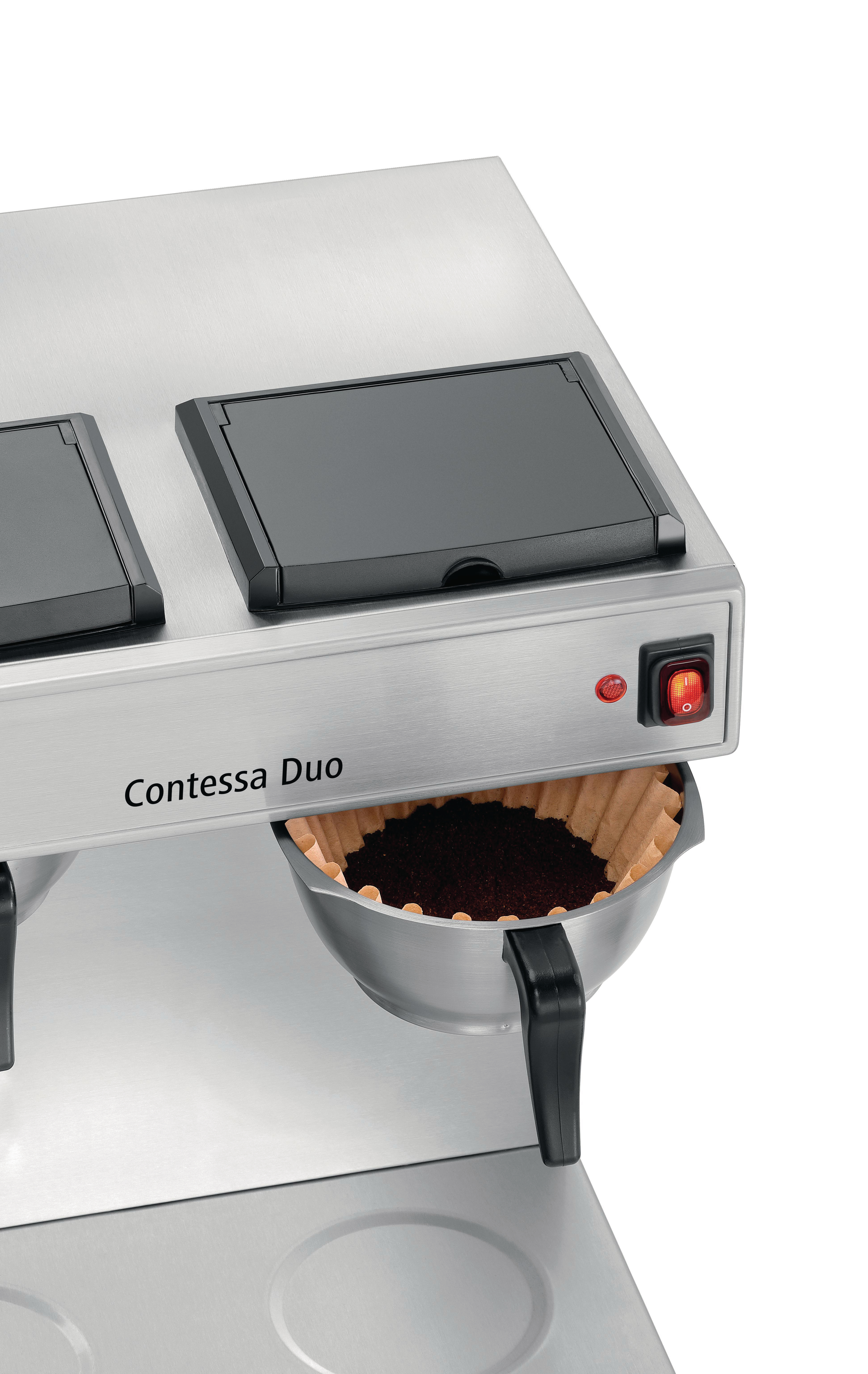 Eine Contessa Duo Kaffeemaschine. Gemahlener Kaffee befindet sich in einem Filter, mit einem roten Ein/Aus-Schalter.