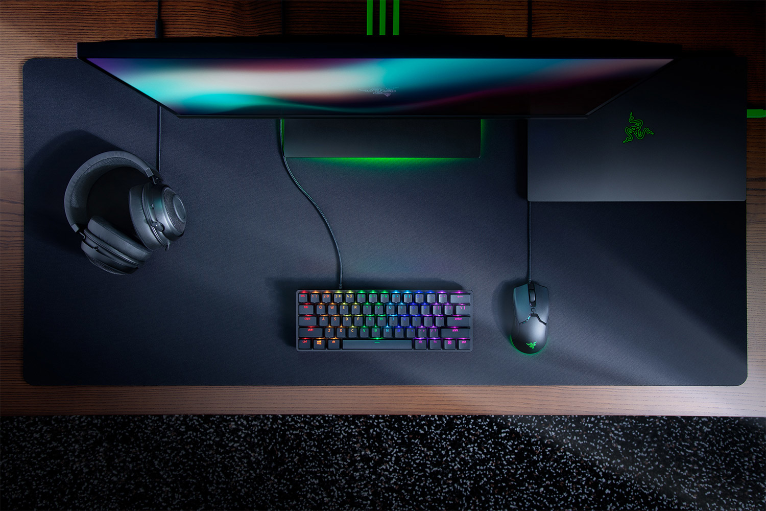 Configurazione gaming: tastiera, mouse, cuffie e monitor. Scrivania e sfondo neri.