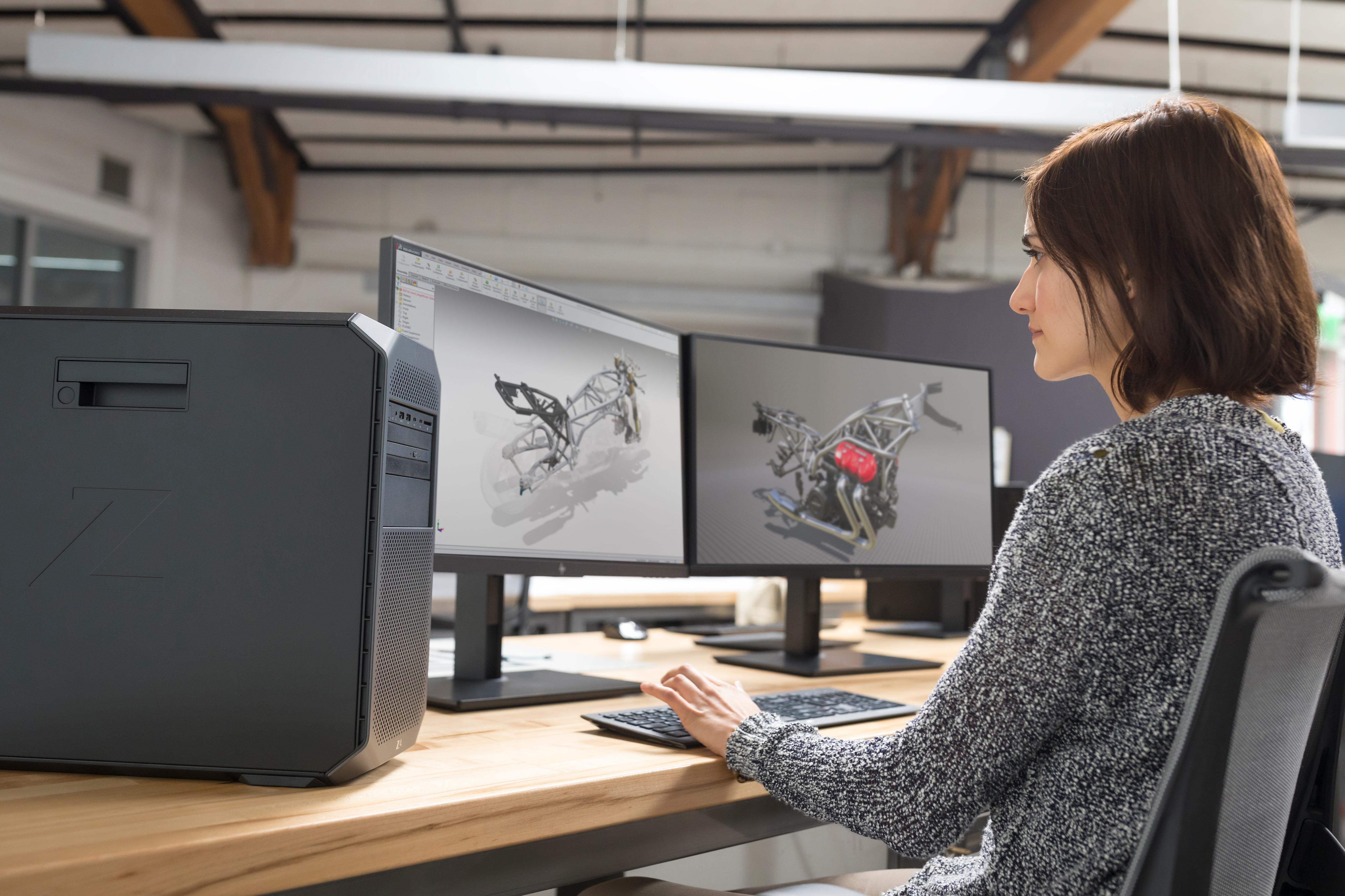 Eine Frau arbeitet in einem modernen Büroumfeld an einem Computer mit zwei Monitoren.