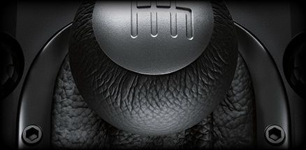 Gros plan sur un pommeau de levier de vitesses noir avec le motif H en relief, entouré de cuir.