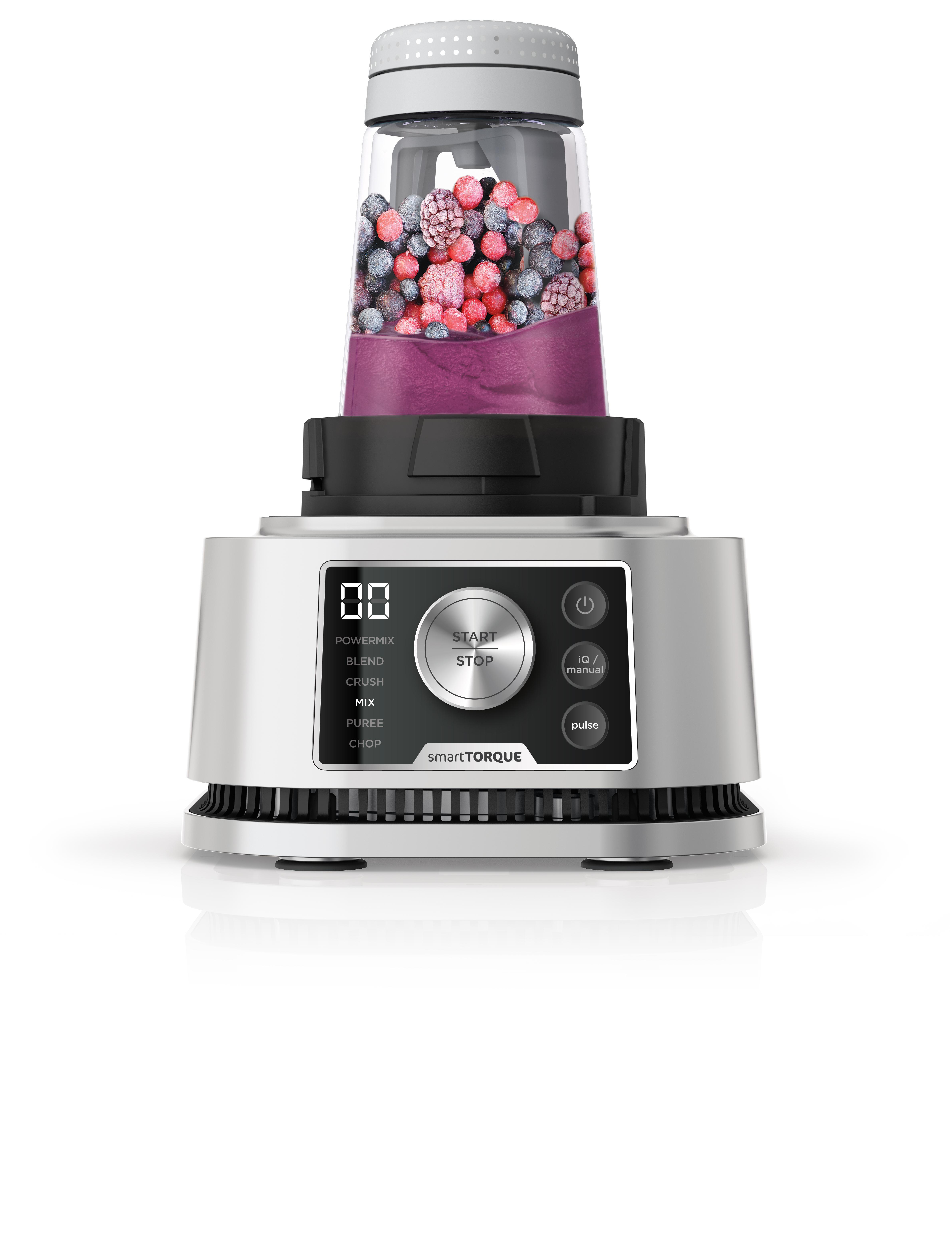 Ein silberner und schwarzer Mixer mit einem transparenten Behälter voller Beeren. Weißer Hintergrund.