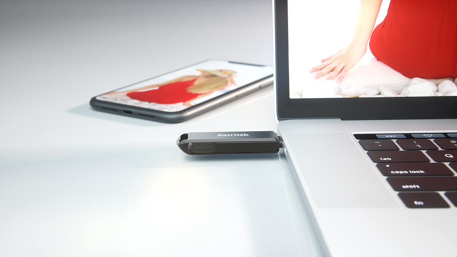 Egy USB meghajtó be van dugva egy laptopba, mellette egy telefon képpel.