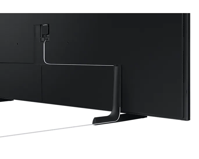Die Rückseite eines Fernsehers mit Ständer. Kabel sind angeschlossen. Die Wand ist schwarz.