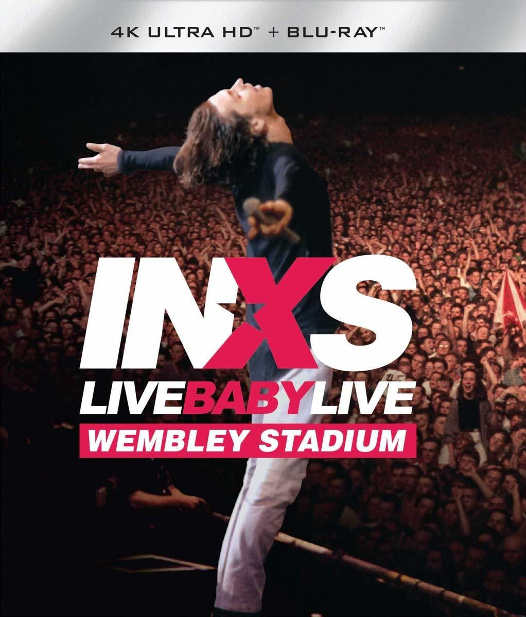 INXS élőben a színpadon egy telt házas stadionban. A zenekar neve vastagon van szedve.