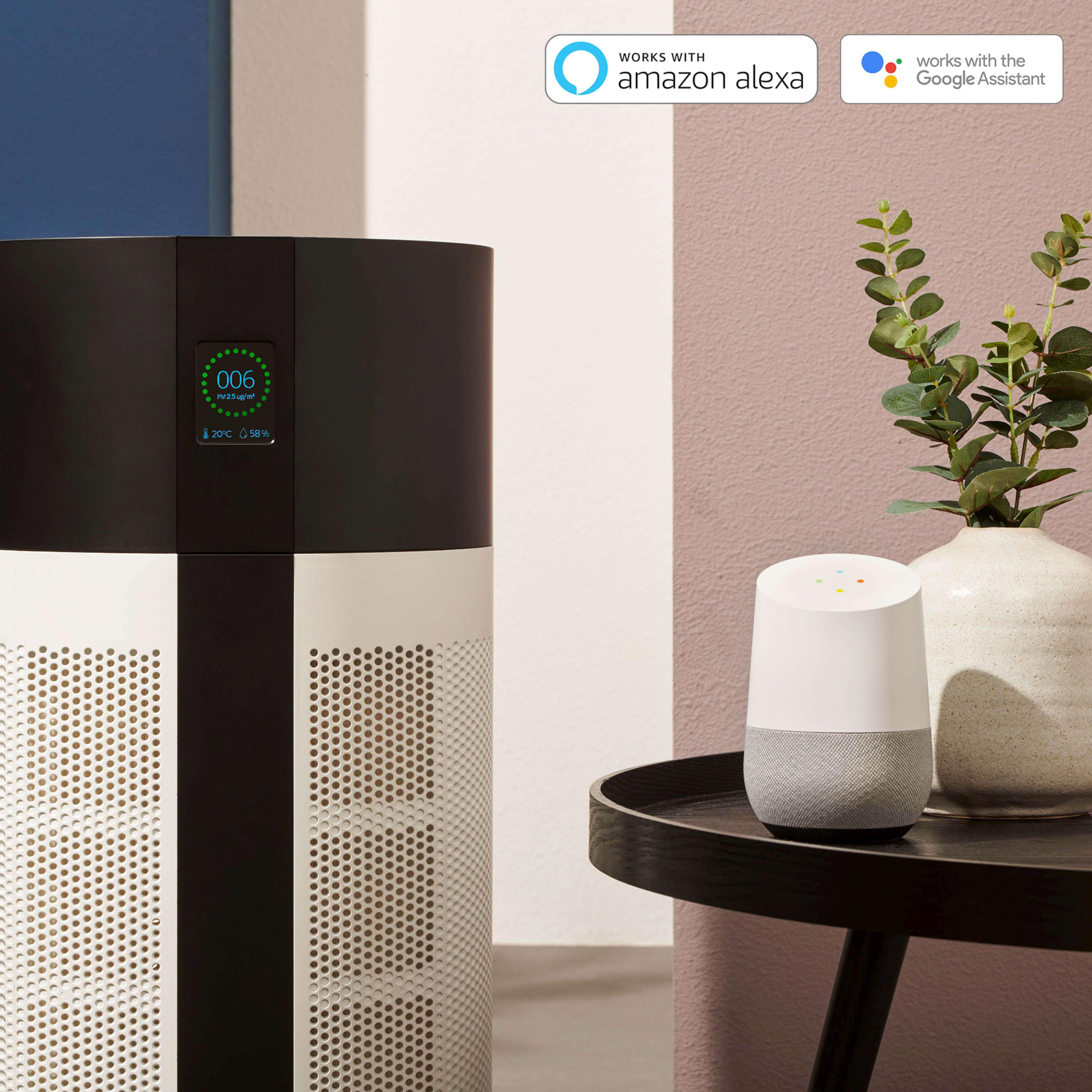 Schwarz-weißer Luftreiniger mit Smart-Lautsprecher. Eine Pflanze steht auf einem Tisch, der Hintergrund ist rosa.