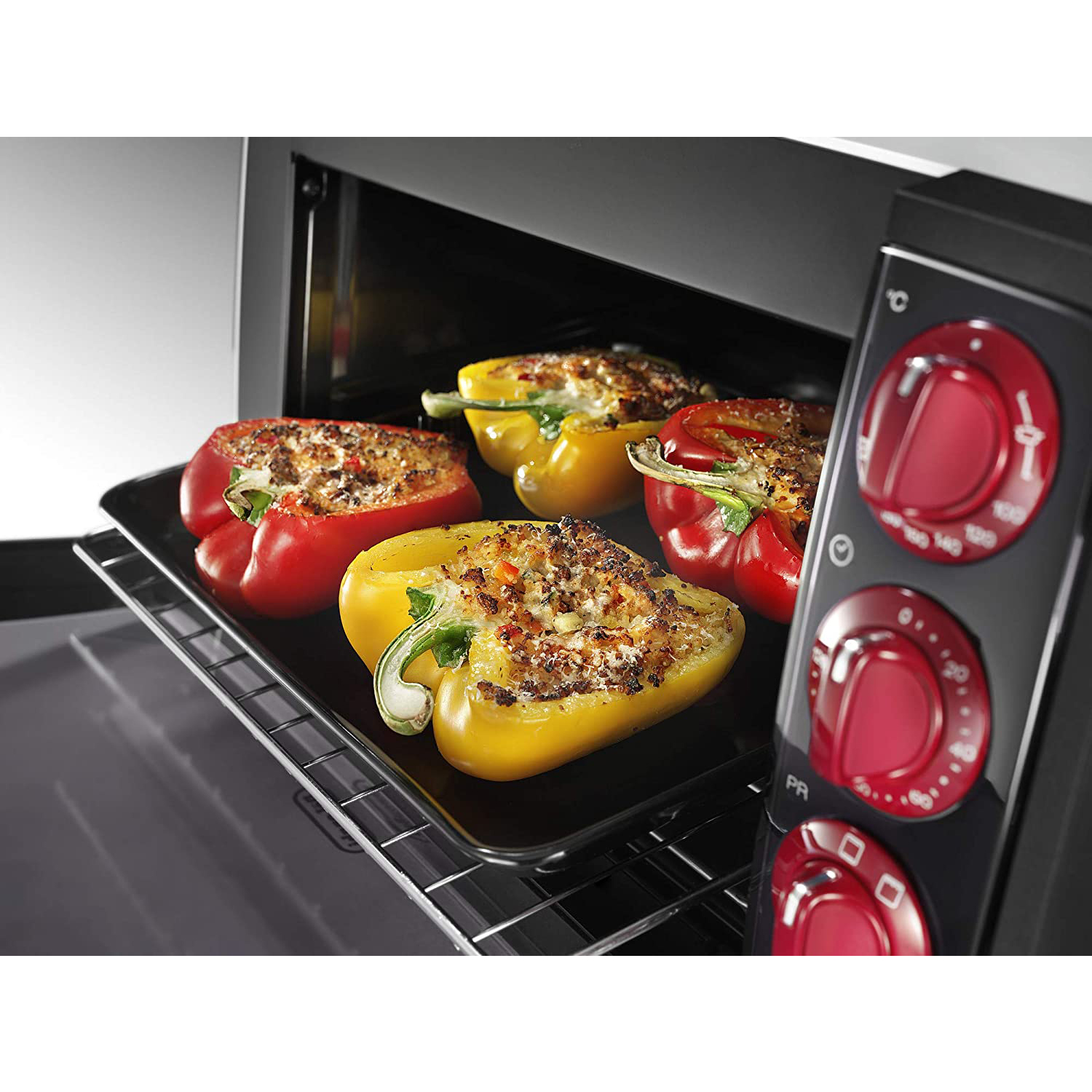 Interno del forno con quattro peperoni ripieni su una teglia nera.