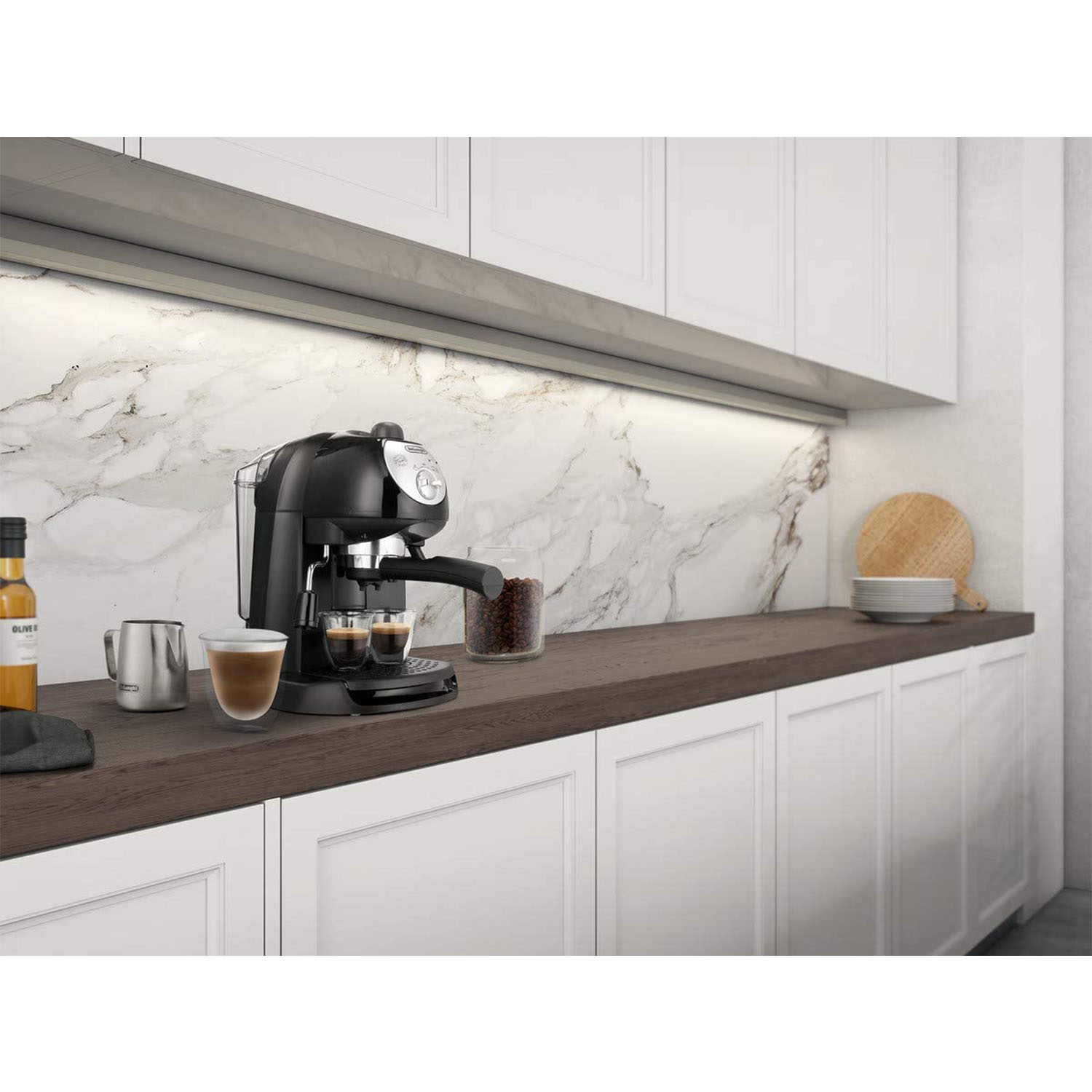 Macchina per espresso nera su un piano di lavoro in legno. Due tazze di caffè presenti. Armadi bianchi.