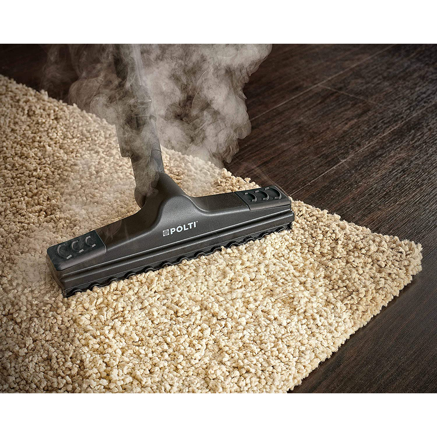Un pulitore a vapore sta pulendo un tappeto di colore chiaro su un pavimento in legno. Il vapore sale.