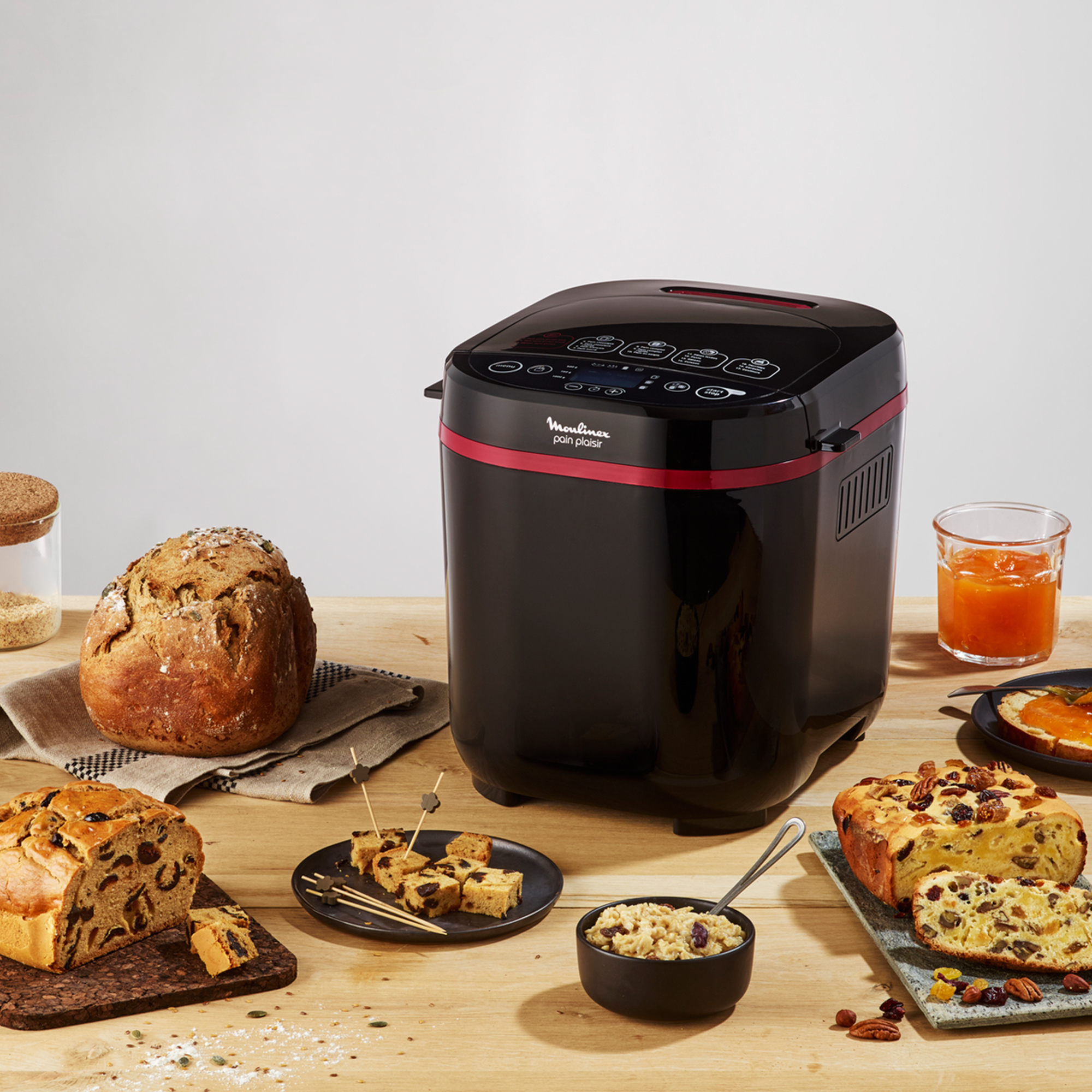 Macchina per il pane nera con cibo su tavolo di legno: pane, toast, snack, marmellata.