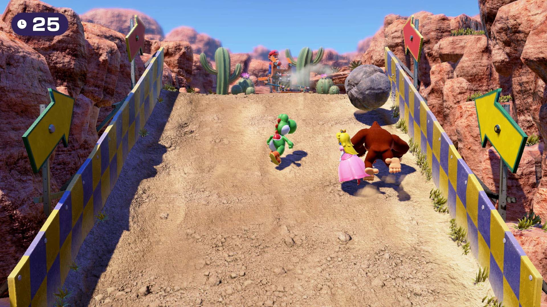 Mario, Peach, Yoshi und Donkey Kong rasen auf einer Rennstrecke mit Barrieren.
