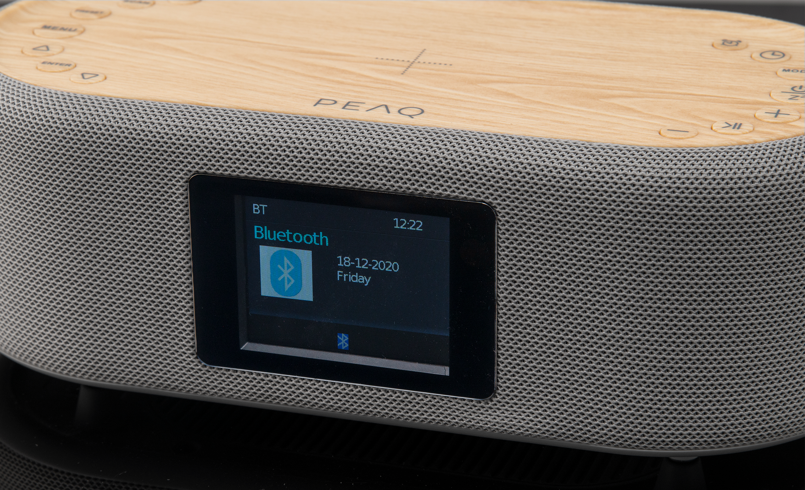 Ein Lautsprecher mit Holzoberseite und einem Bildschirm, der Bluetooth-Verbindungsinfos anzeigt.