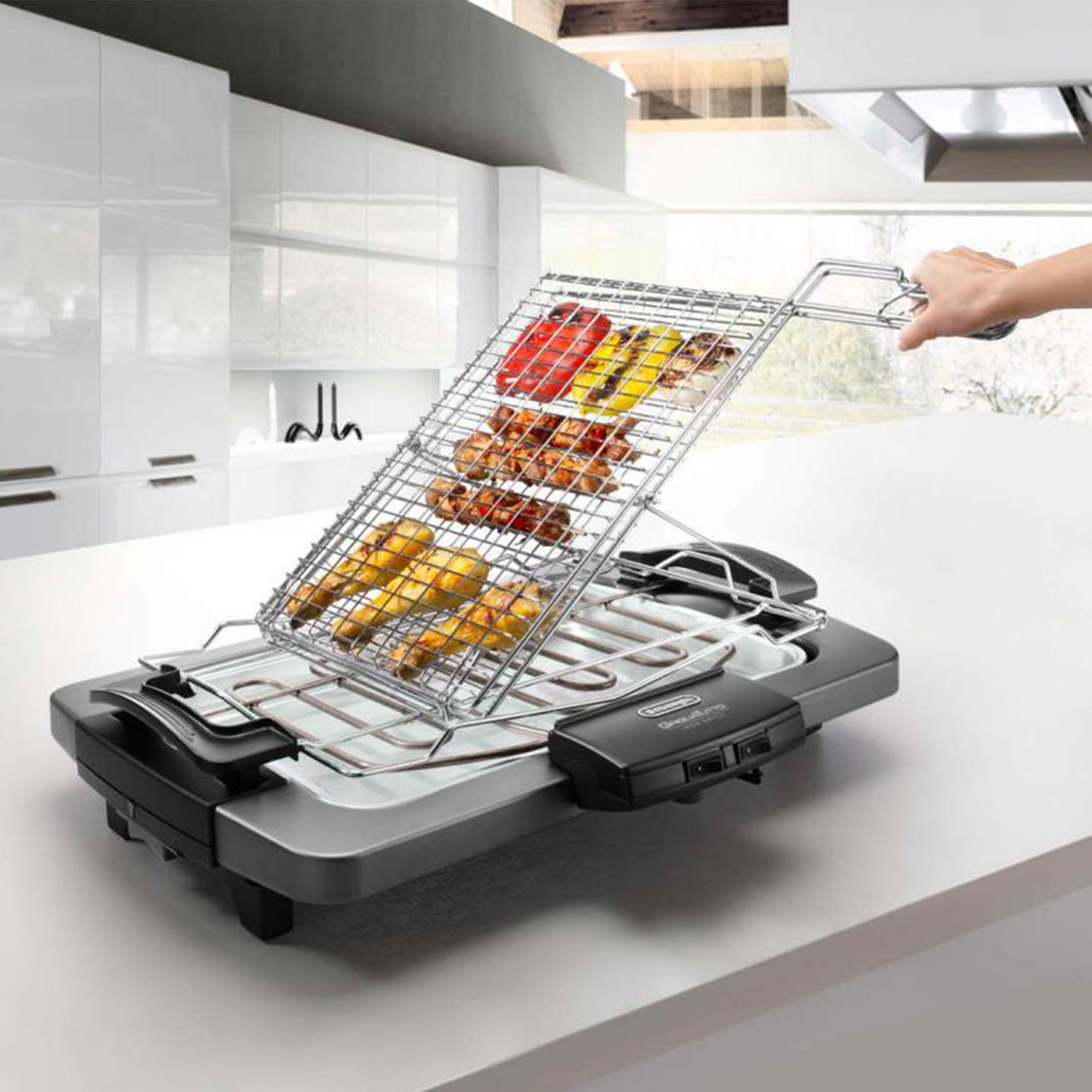 Una griglia elettrica DeLonghi con vari cibi su un ripiano da cucina bianco.