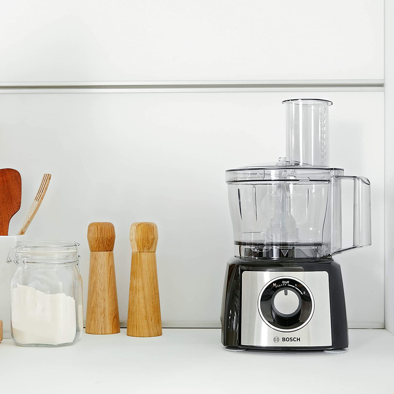 Robot da cucina Bosch, superficie bianca, saliere e pepiere in legno e un barattolo.