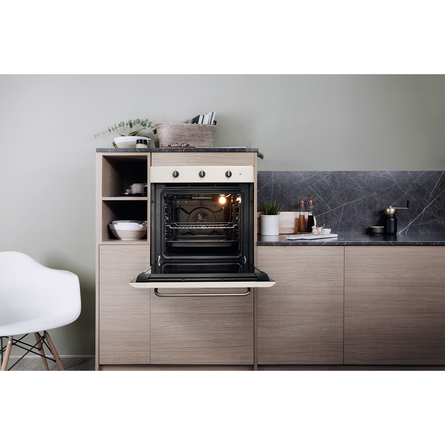 Cucina con forno, porta aperta. Mobili in legno chiaro, piano di lavoro nero, sedia bianca.