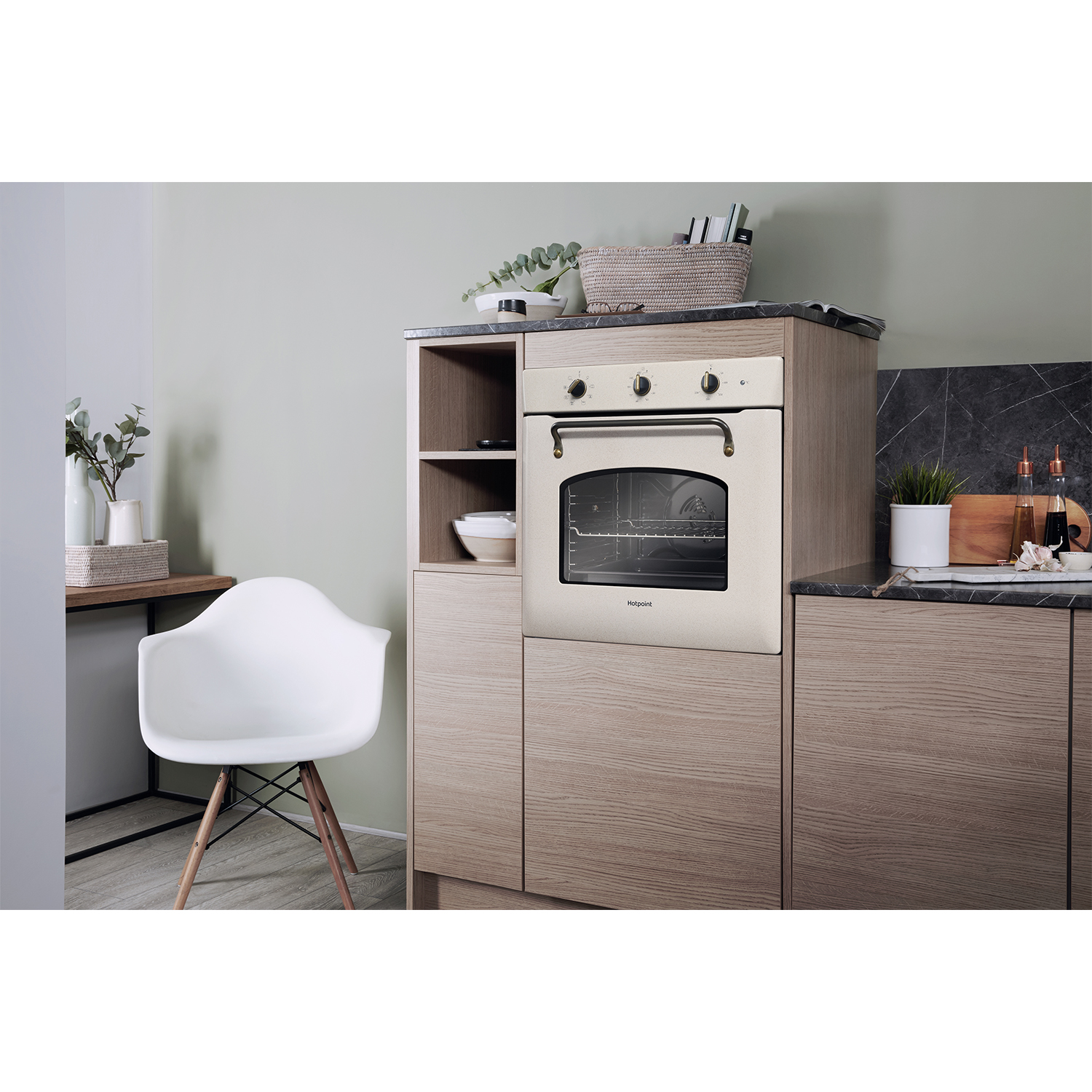 Una cucina con forno a incasso, mobili in legno, una sedia bianca e piante.