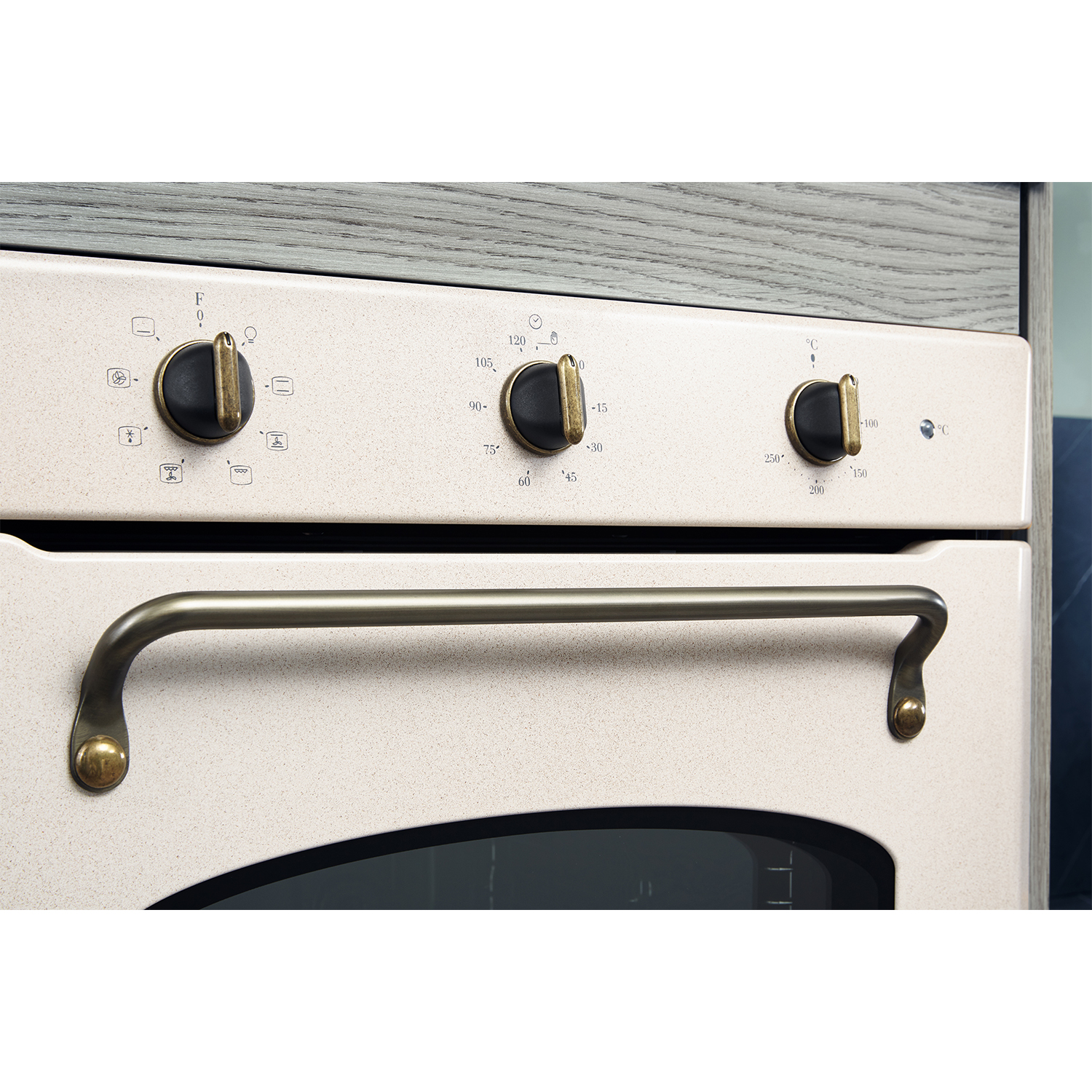 Un pannello di controllo del forno con manopole. Il pannello è bianco sporco, con dettagli in metallo e neri.