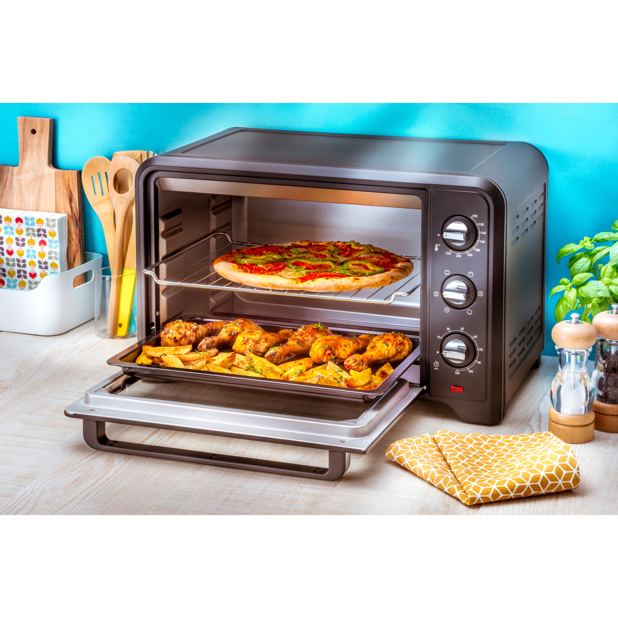 Un forno nero aperto con pizza e cosce di pollo dentro. Un vassoio di patatine sulla porta aperta.