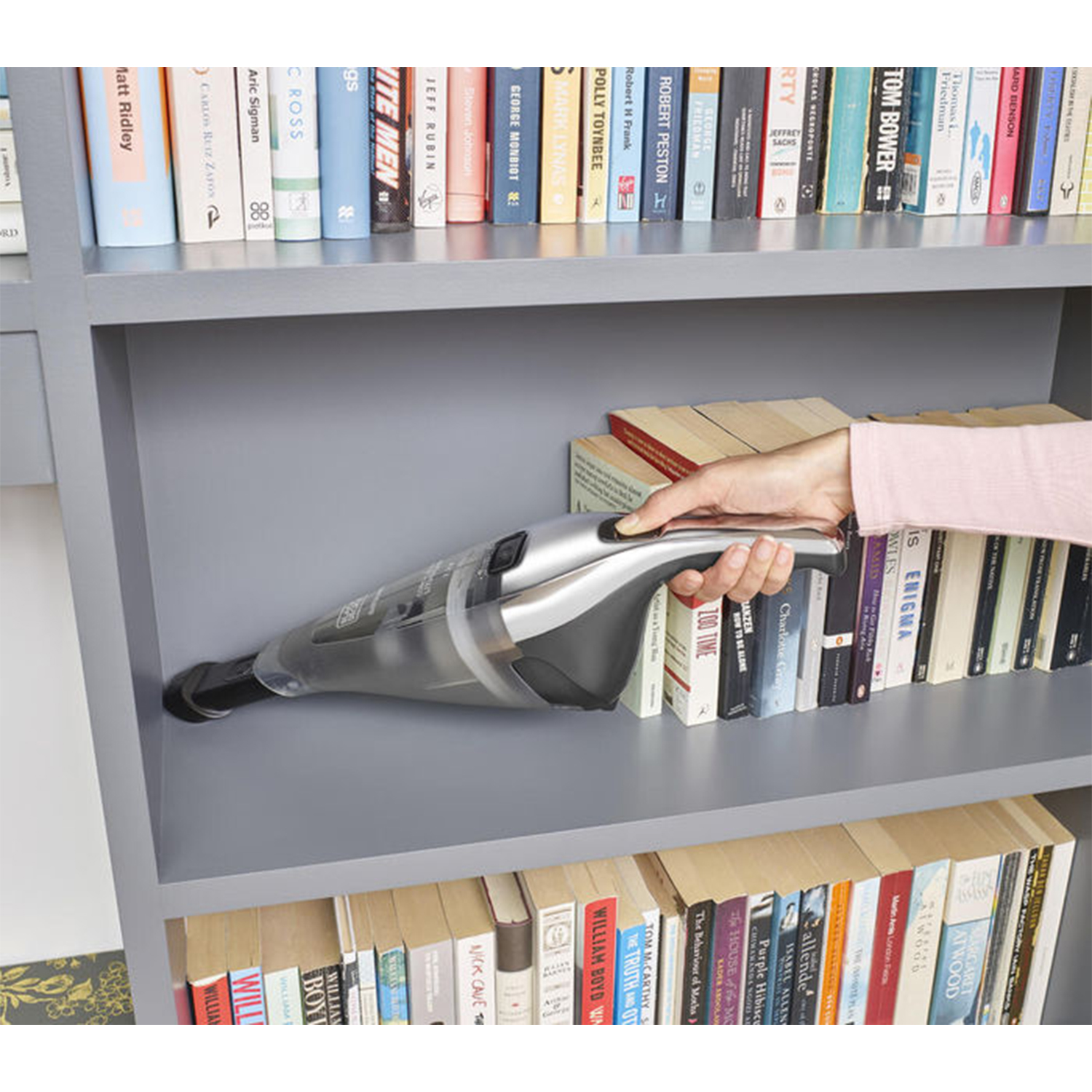 Mano che aspira una libreria, libri visibili.