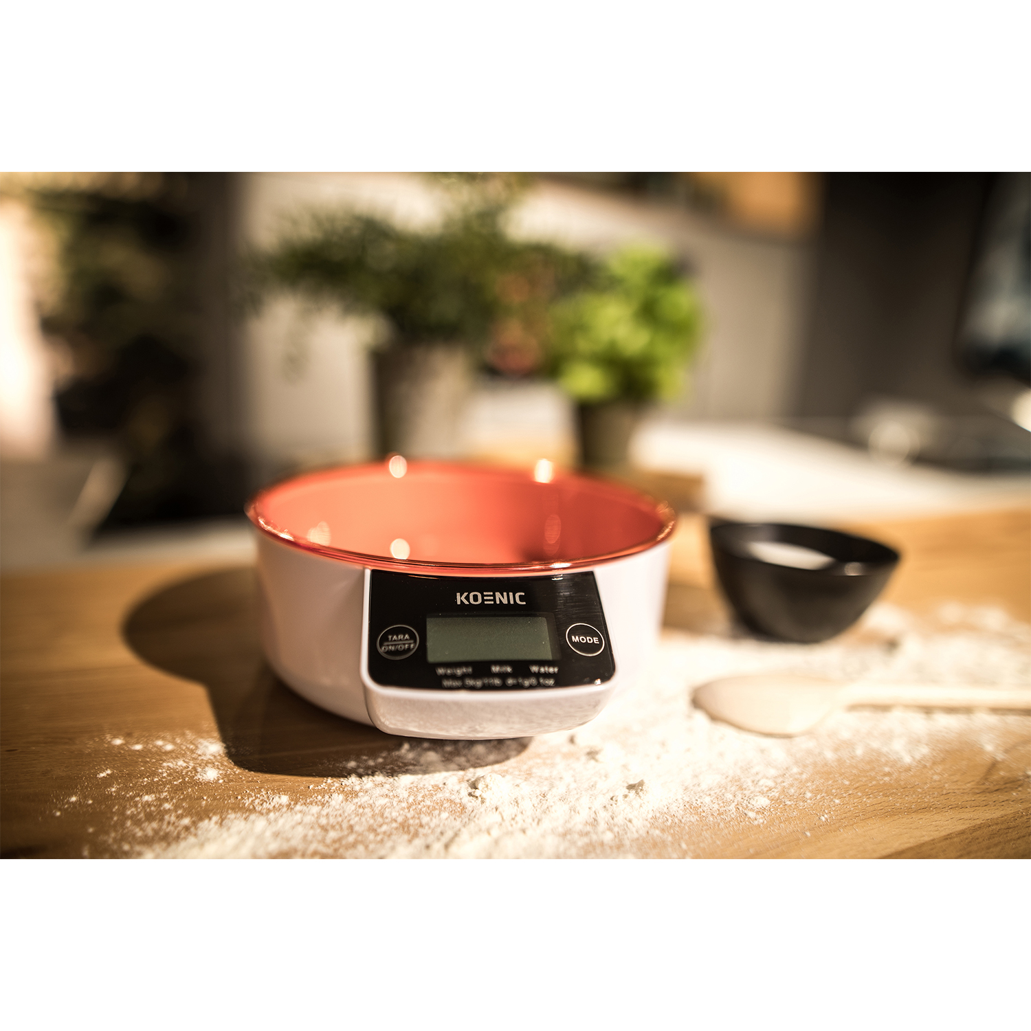 Una bilancia da cucina con una ciotola rossa, farina e altri oggetti su una superficie di legno.