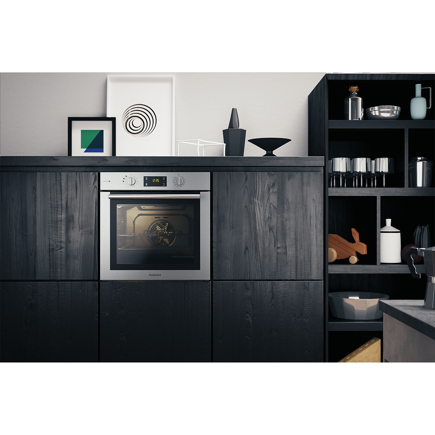 Una cucina moderna con forno in acciaio inossidabile, mobili neri e arte incorniciata sulla parete.