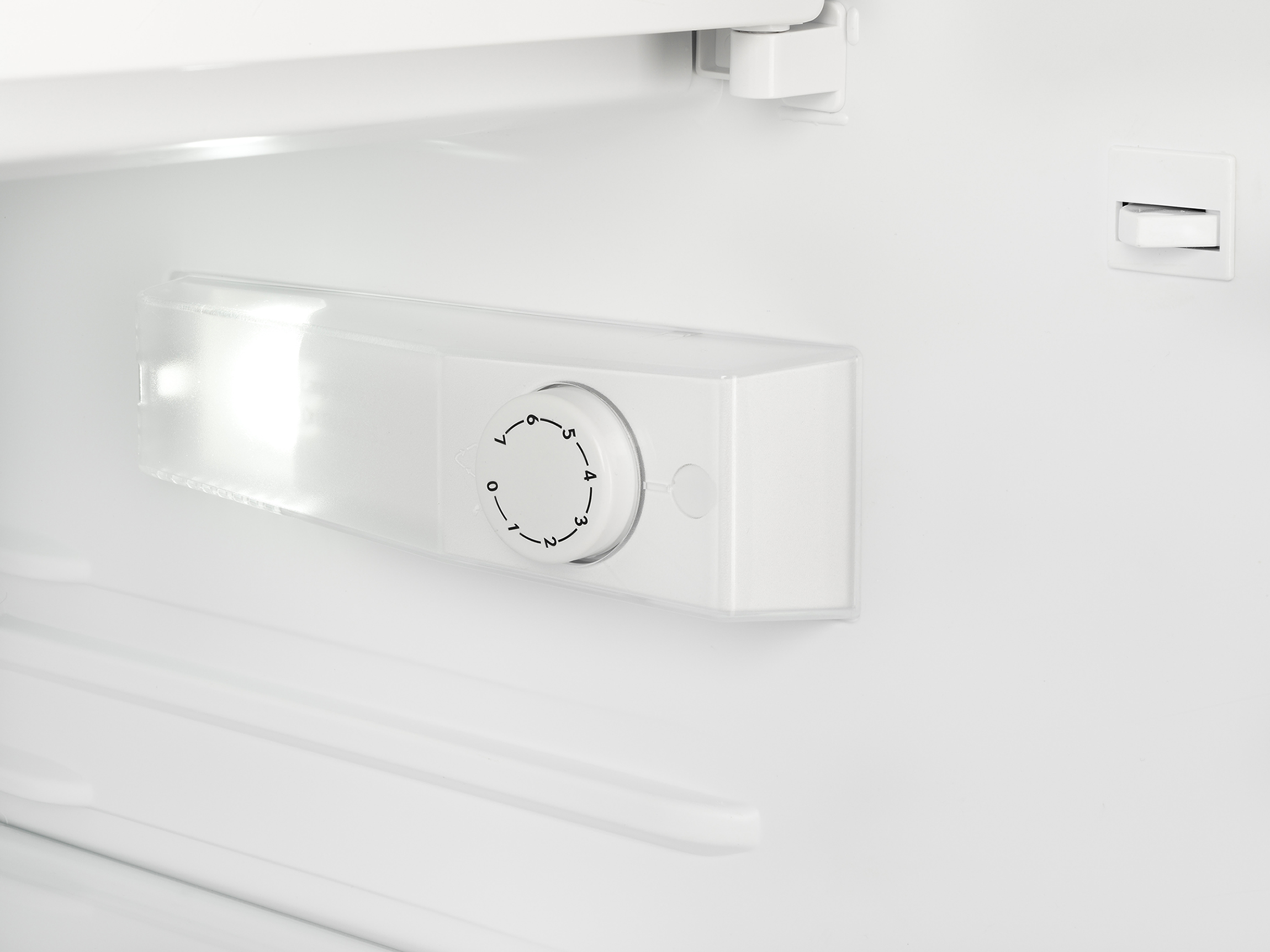 Binnenkant van een koelkast. Een wit licht en een temperatuurregeling zijn zichtbaar. Witte planken zijn binnen.