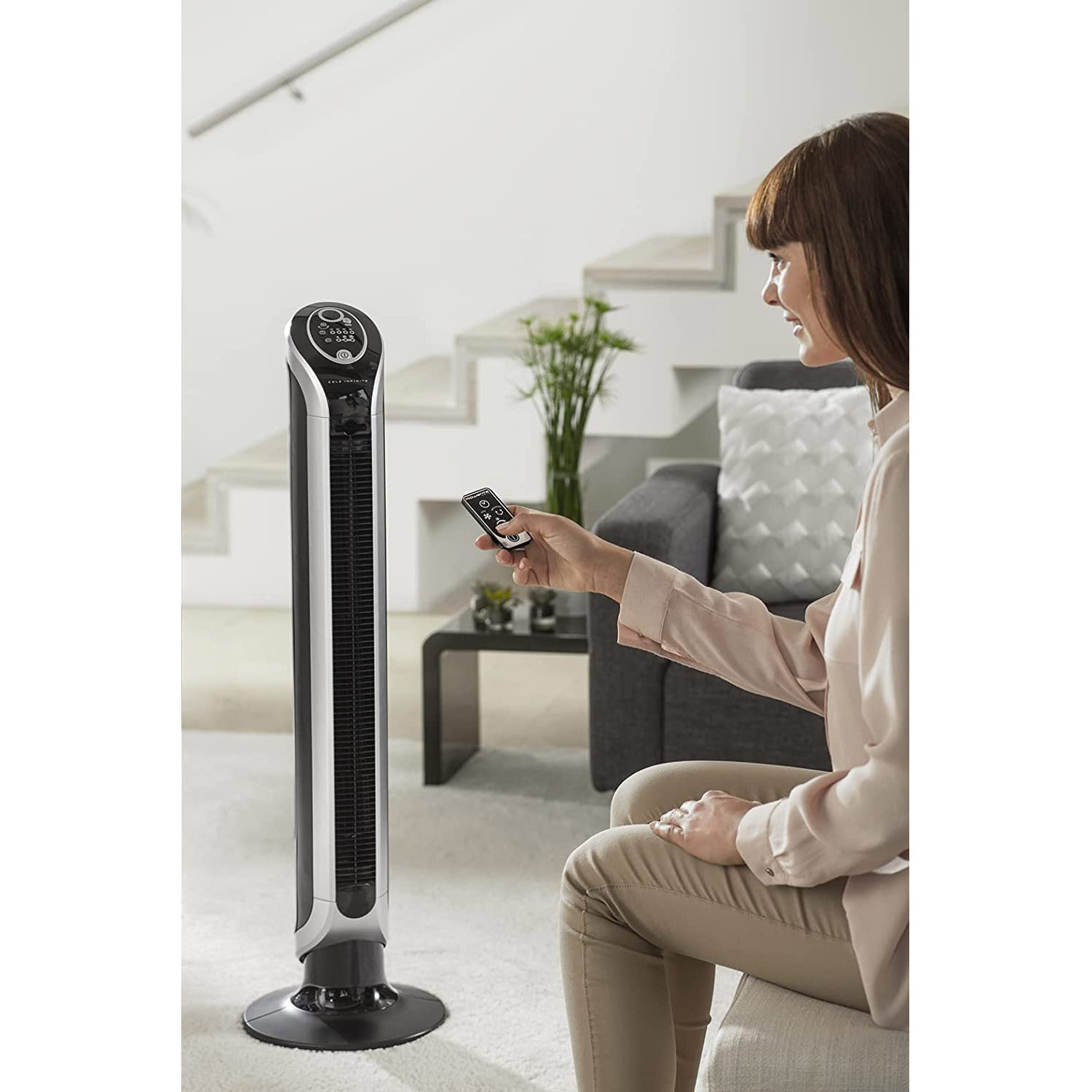 Donna usa telecomando per un ventilatore alto nero e argento.