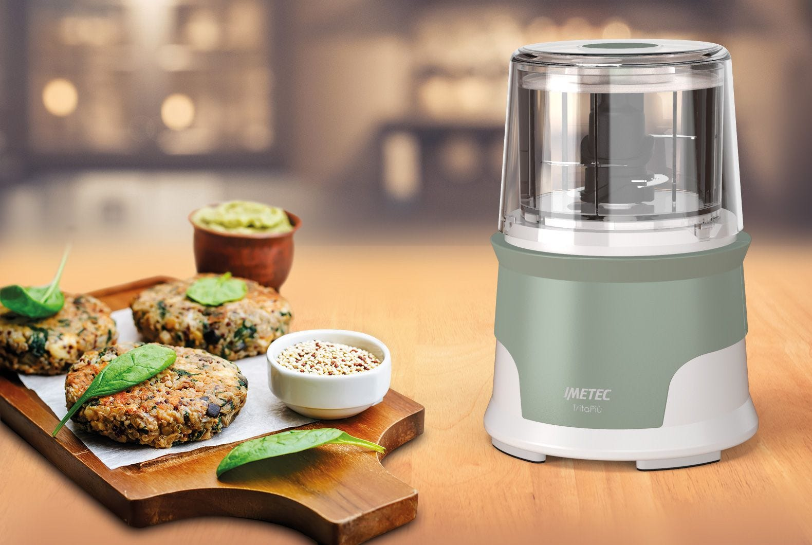 Egy konyhai robotgép és zöldségburgerek egy fa felületen. Egy tál quinoa és guacamole is látható.