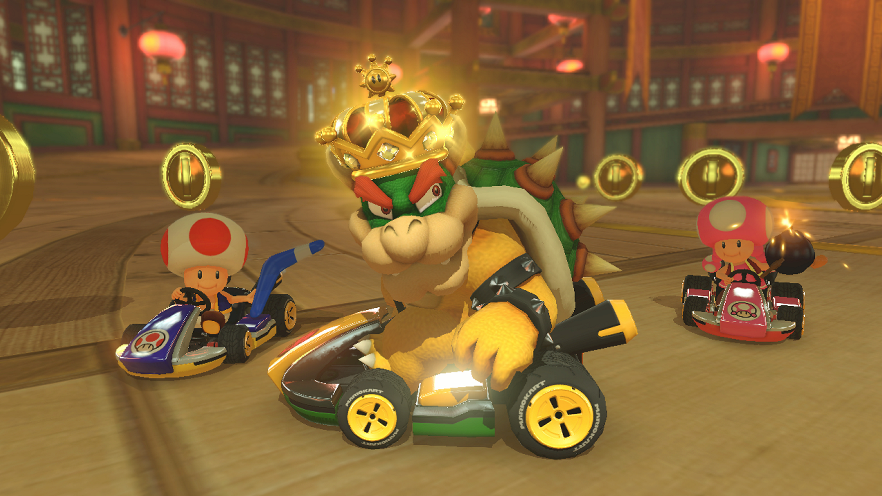 Bowser in einem Kart mit Krone, der ein Rennen anführt. Toad und ein rosa Toadette sind in anderen Karts.