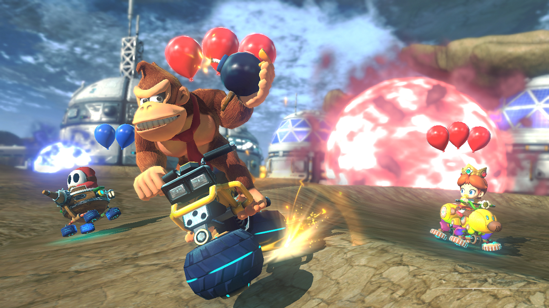 Donkey Kong in einem Kart wirft eine Bombe, andere rasen auf einer Wüstenstrecke.