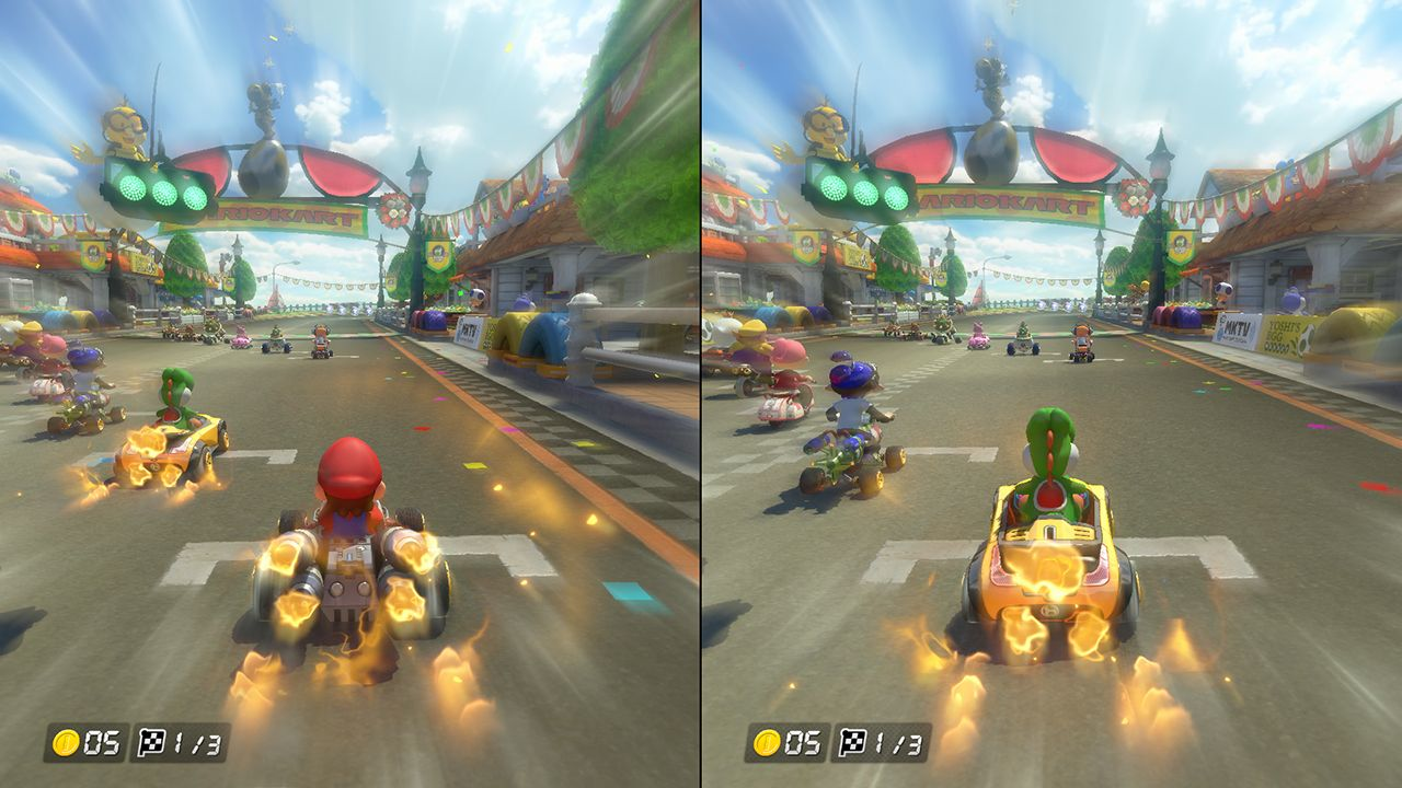 Uno schermo diviso di un gioco di Mario Kart. Le auto corrono su una strada. Lo sfondo mostra una città e un cielo blu.