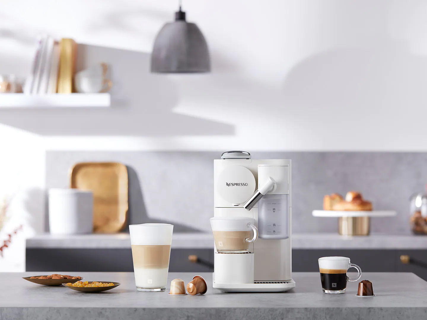 Une machine Nespresso blanche avec des tasses et des dosettes de café.
