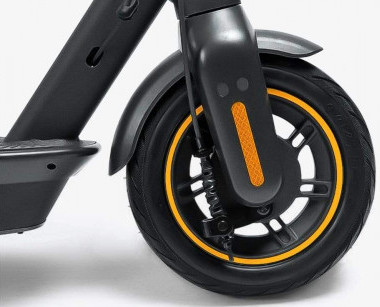 Gros plan sur une roue de trottinette électrique. Le pneu noir a une bande jaune. Le garde-boue et le cadre sont noirs.