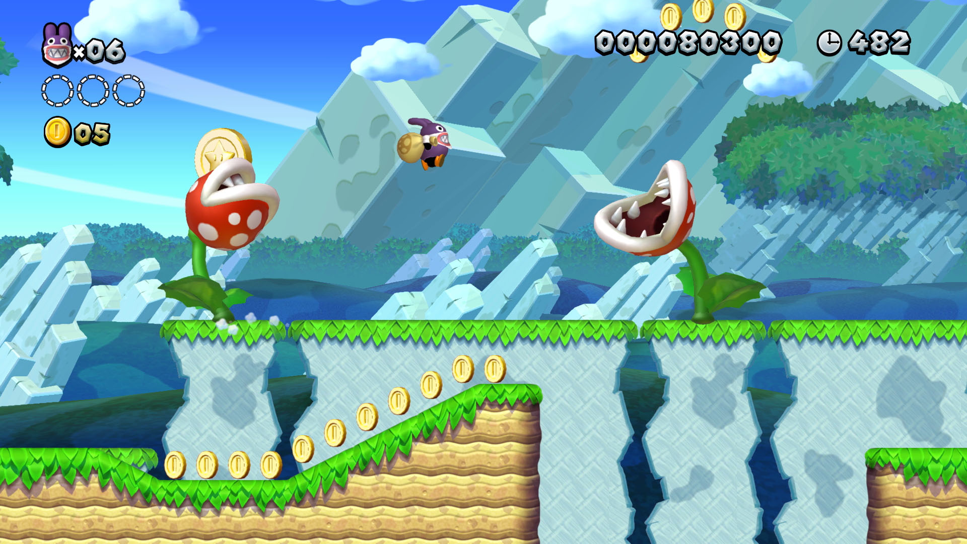 Schermata di un livello di videogioco. Un personaggio salta sopra una Pianta Piranha e monete.