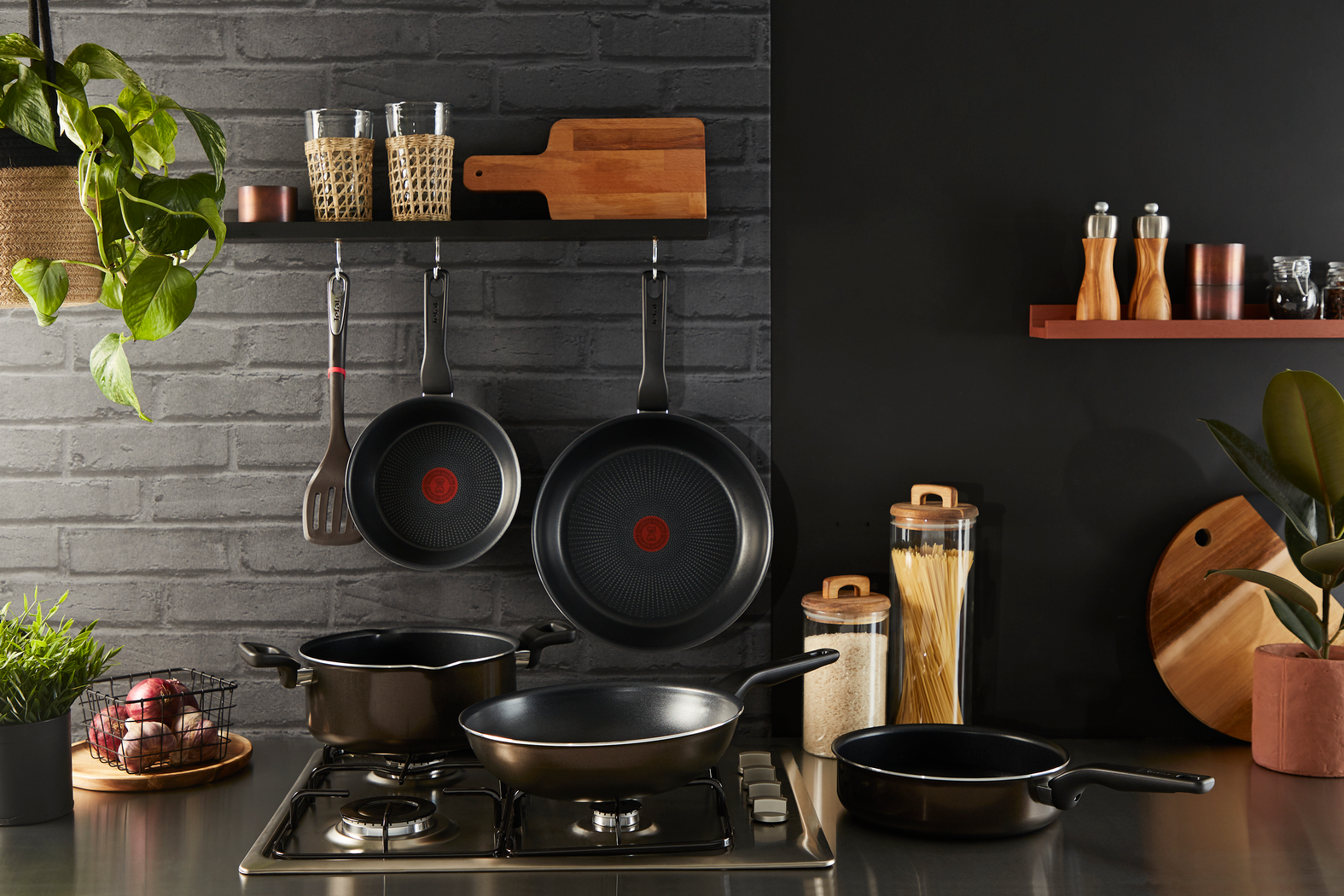 Keuken scène. Pannen, potten op fornuis, keukengerei hangt boven. Planten, houten snijplank.